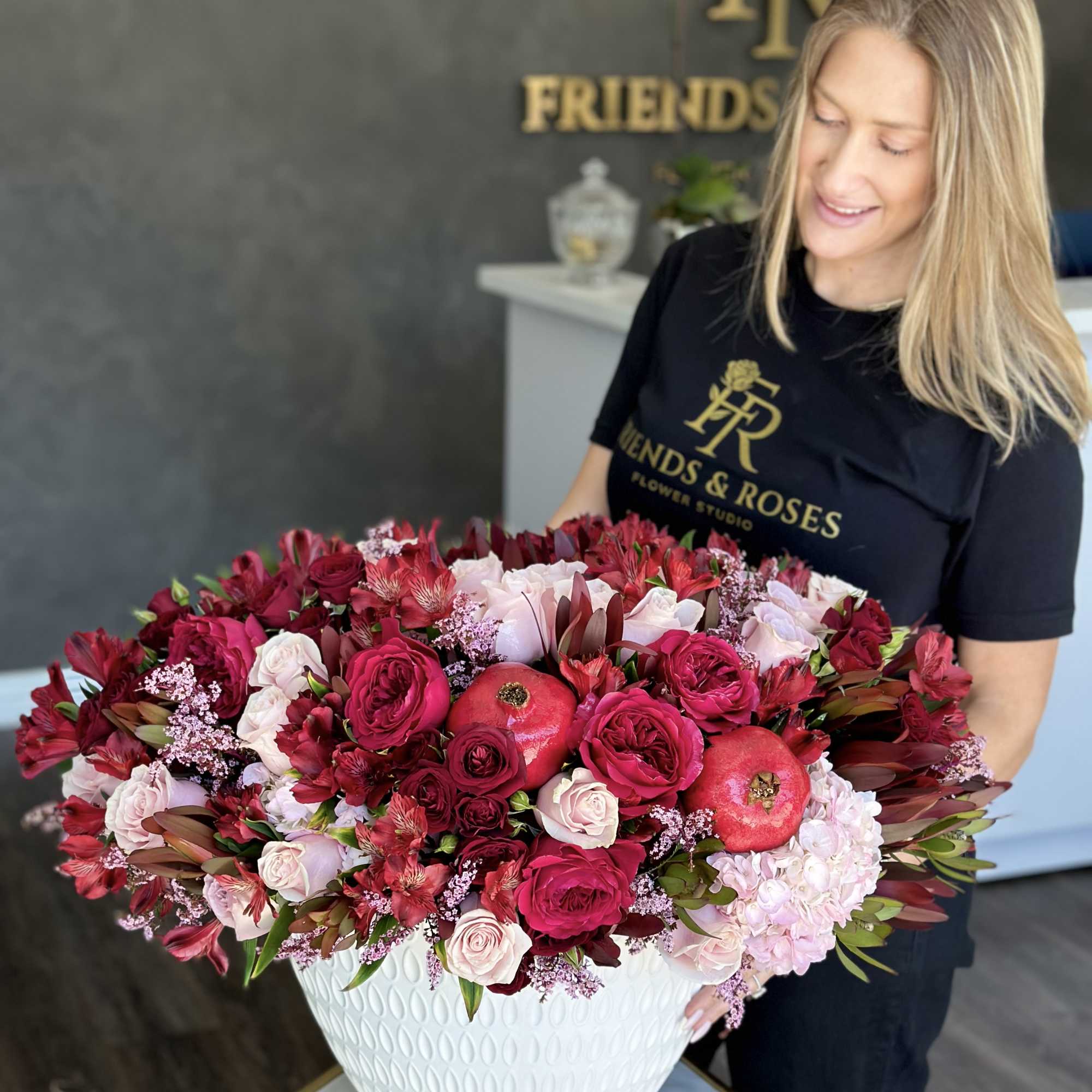 Large pink and red rose arrangement in a white vase