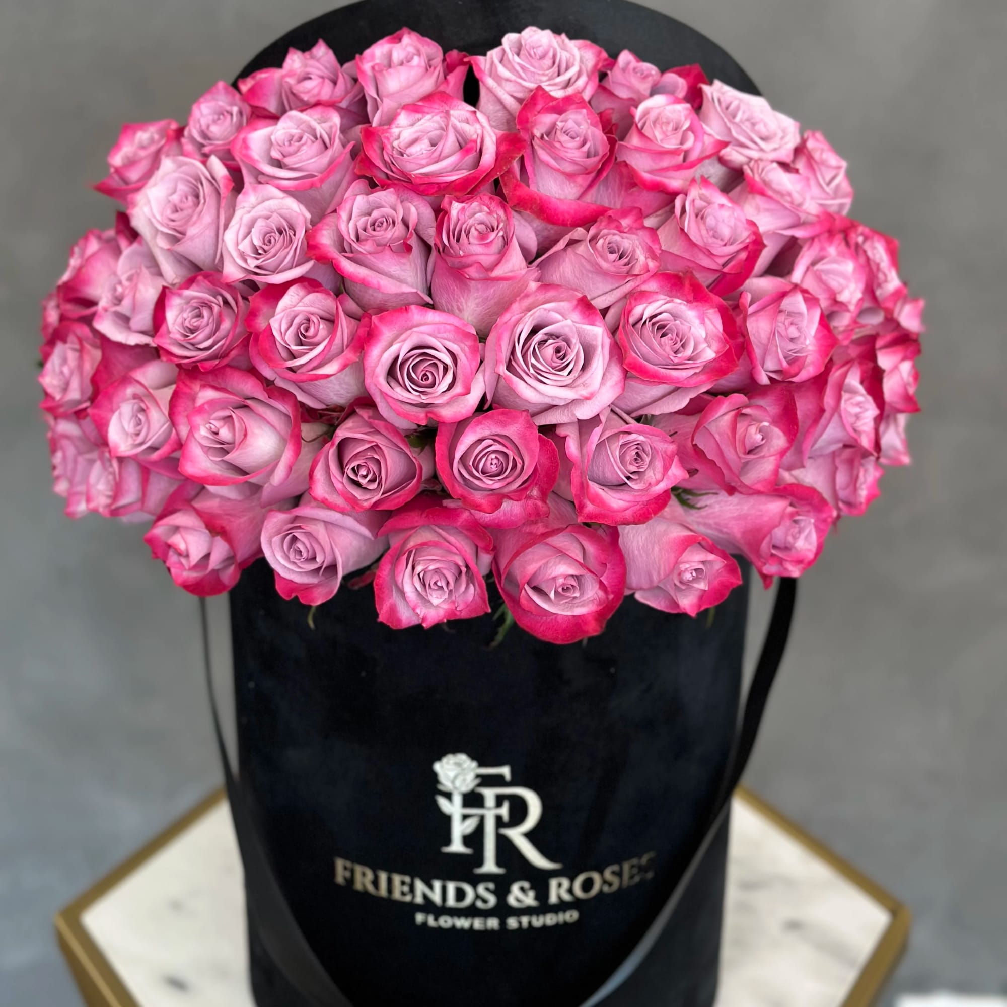Pink roses arranged in a black hatbox