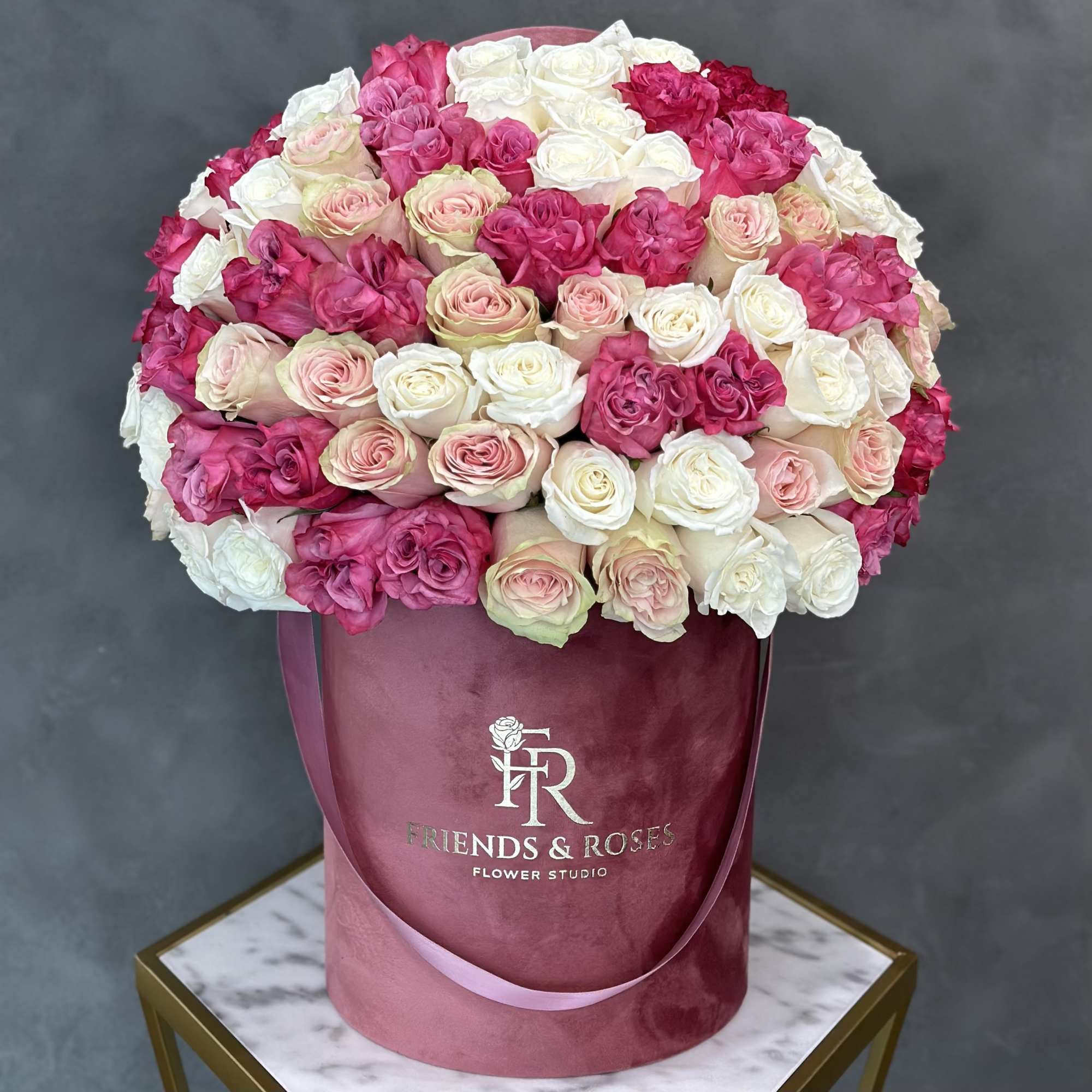 Bouquet of pink and white roses in a pink hatbox