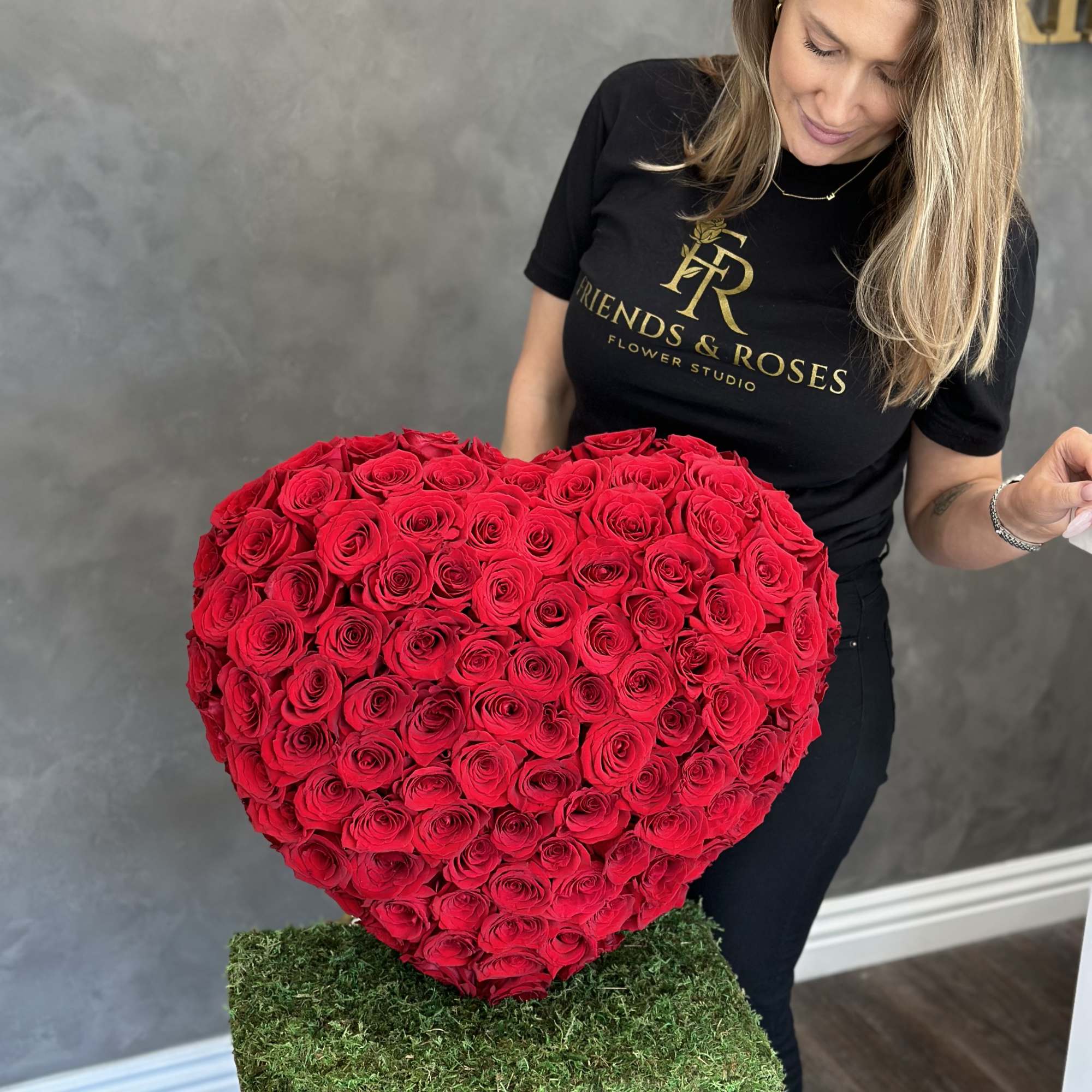 Heart-shaped arrangement of red roses held by a woman