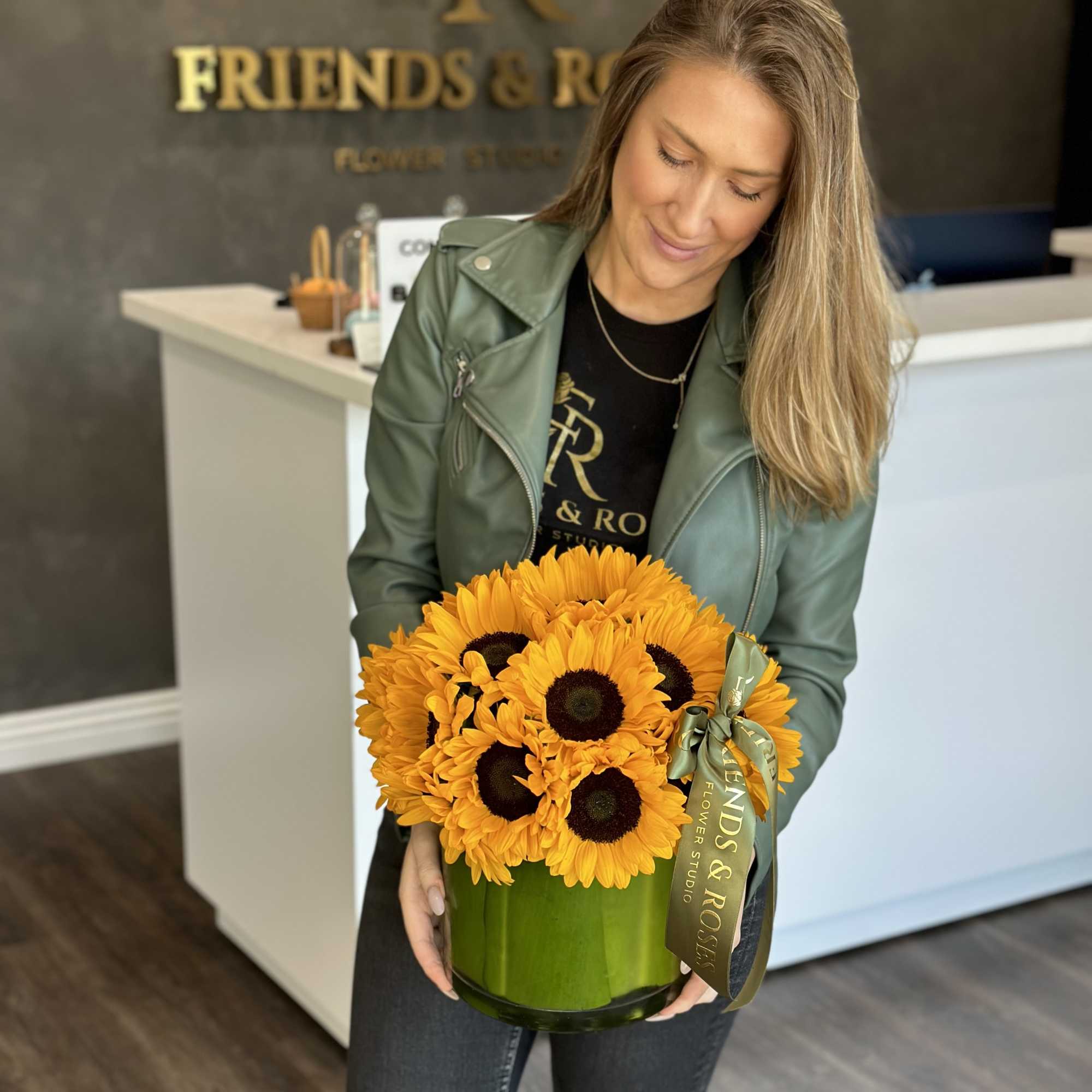 Woman holding a green vase of bright yellow sunflowers