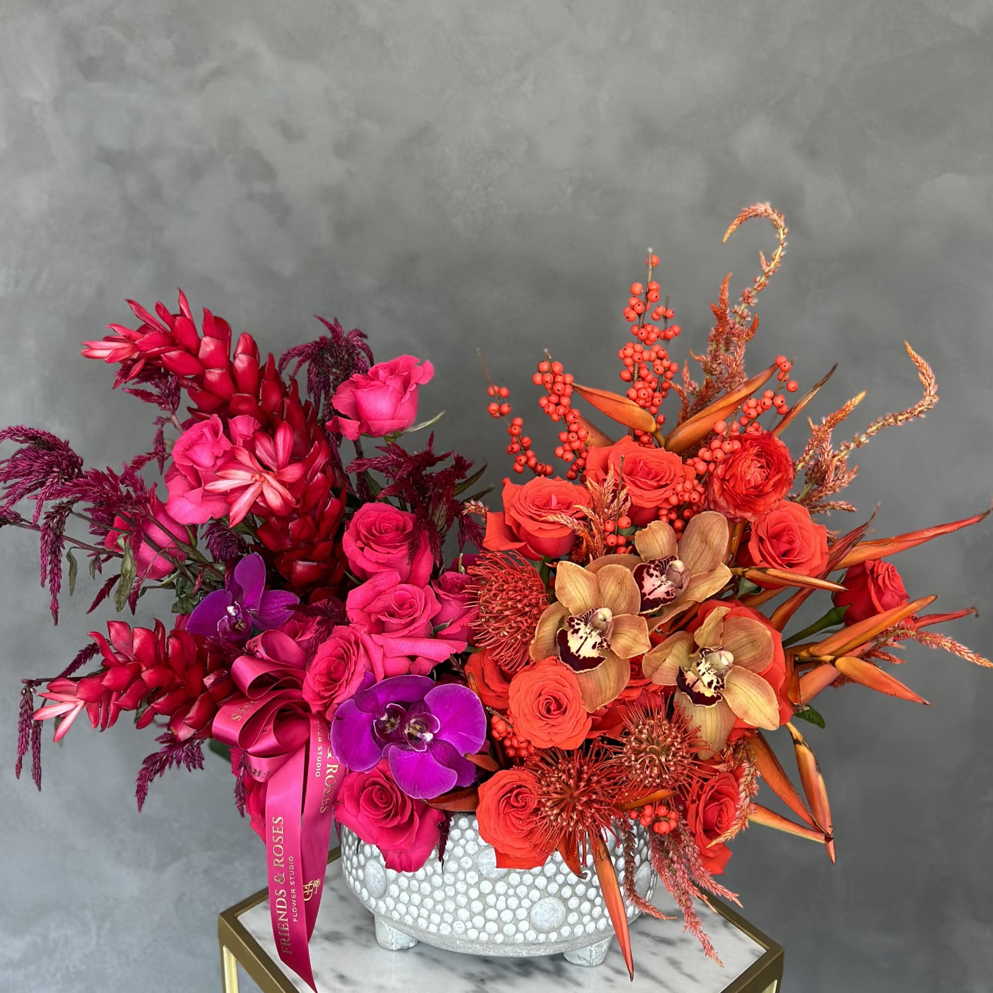 Bright pink and orange floral arrangement in a white textured vase