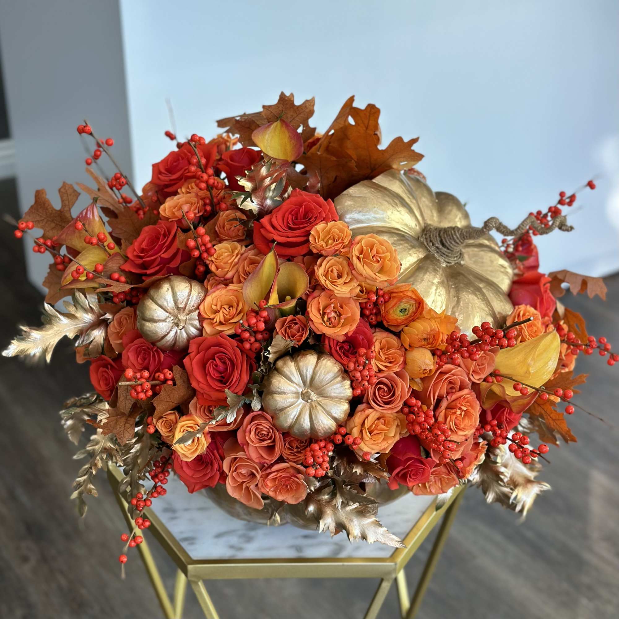 Autumn bouquet of red and orange roses with gold pumpkins