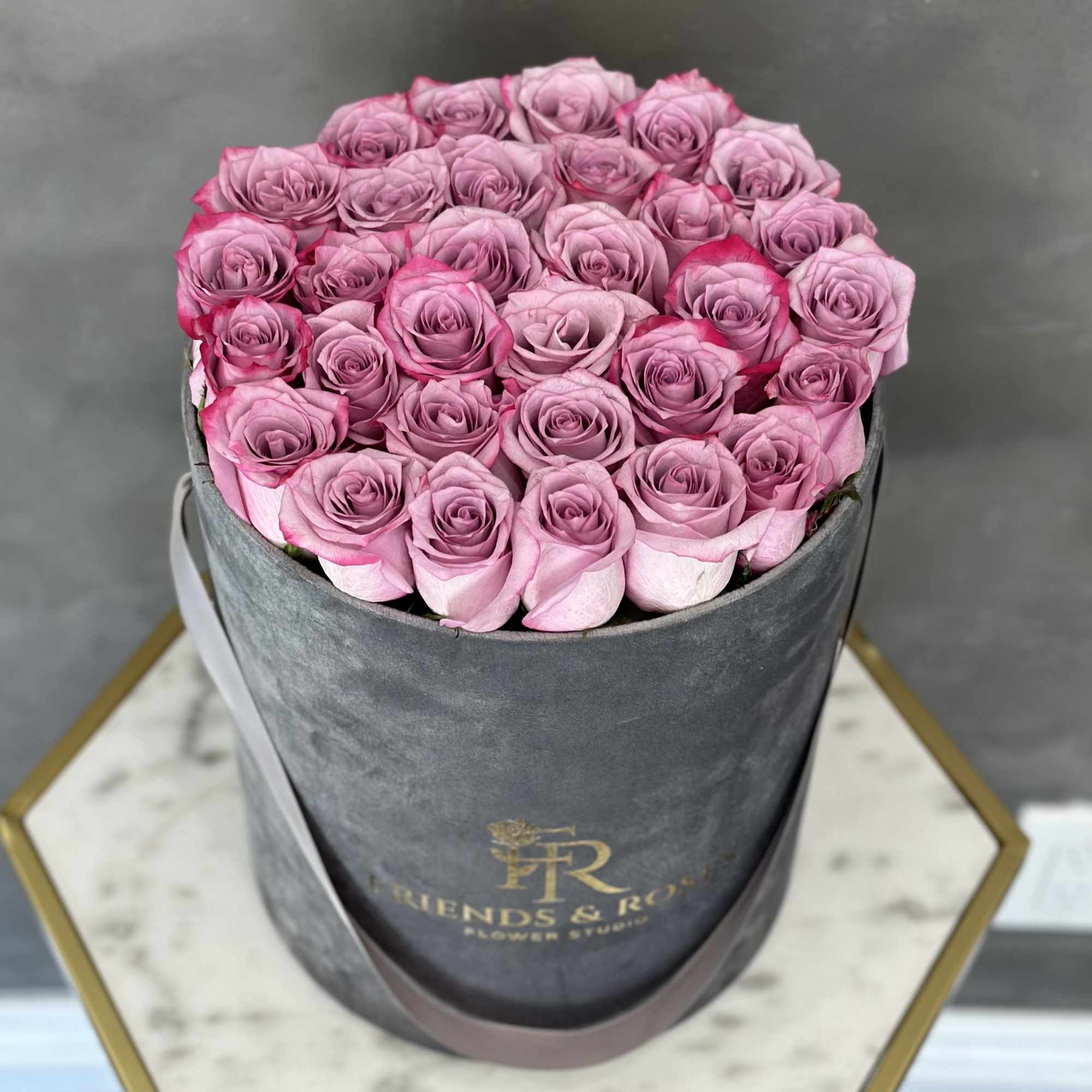 Pink roses arranged in a round gray hat box