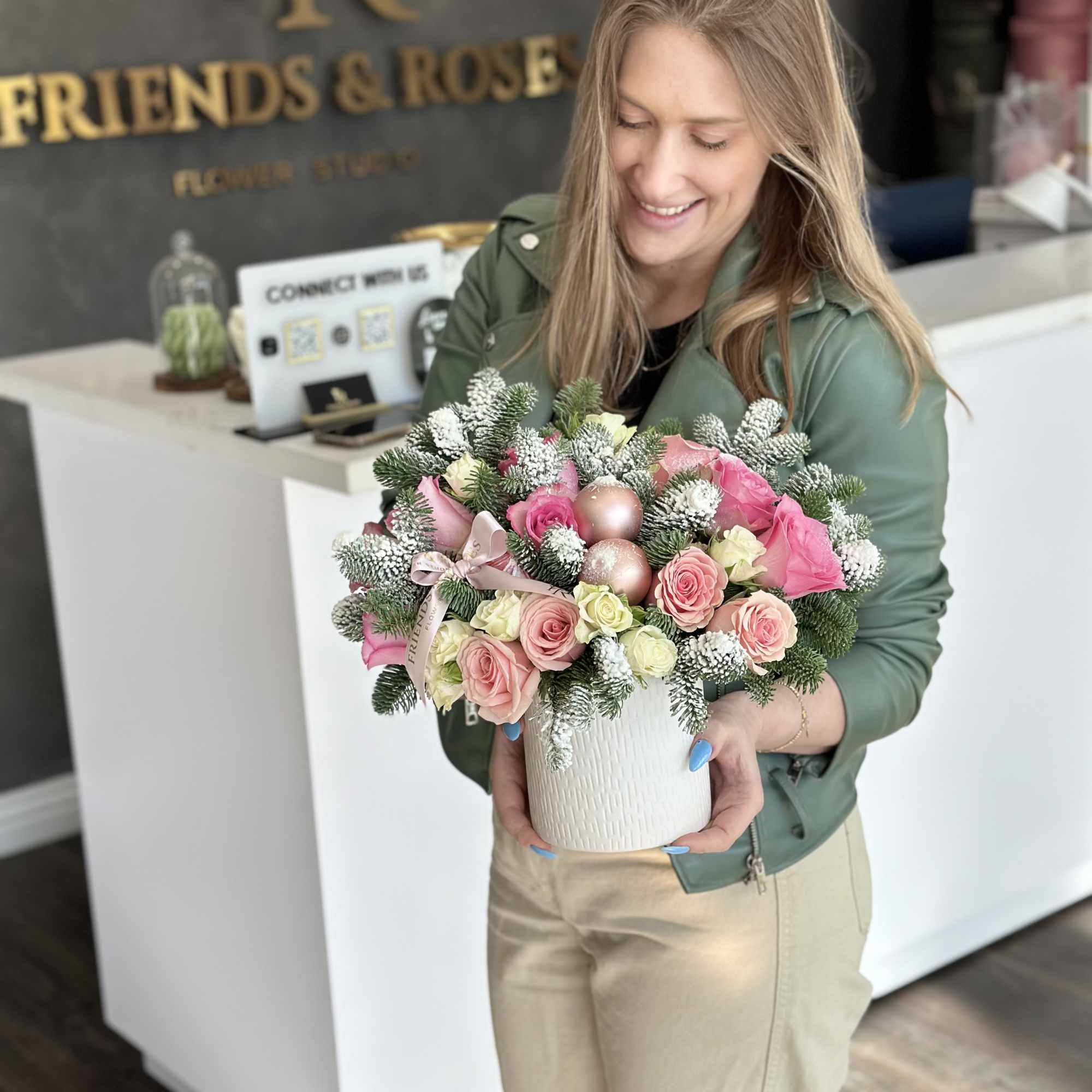 Woman holding a pink rose arrangement in a white vase