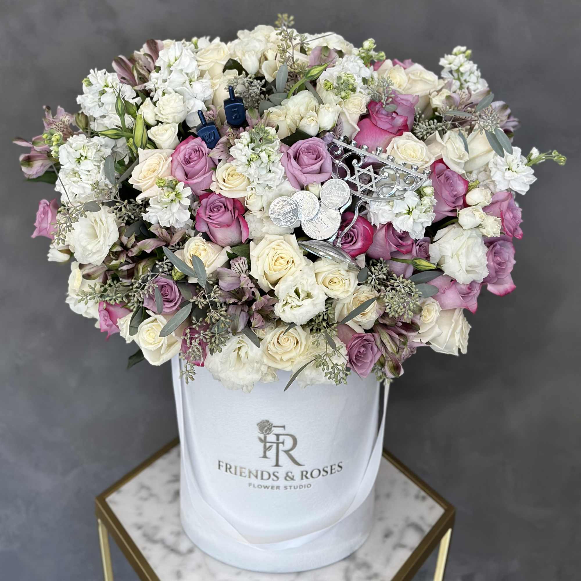 Pink and white roses arranged in a white hat box