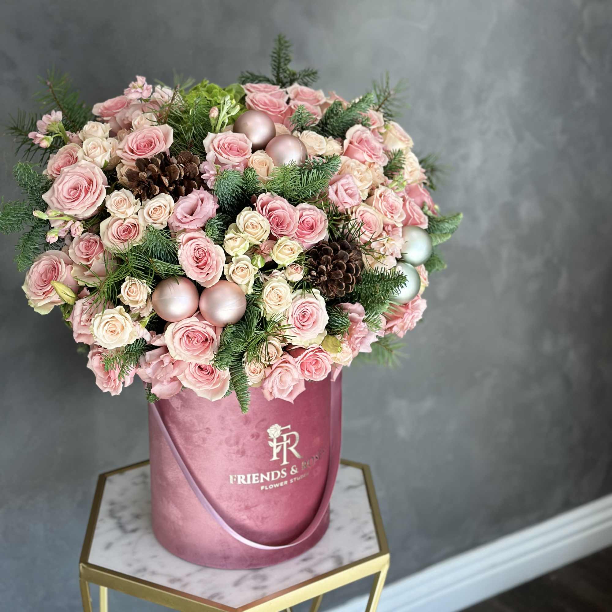 Pink and cream rose bouquet in a pink hatbox with pinecones and ornaments