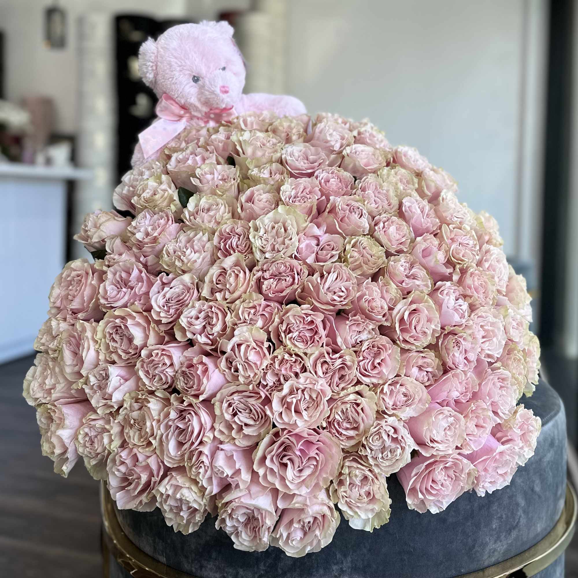 Large bouquet of pale pink roses with a pink teddy bear on top