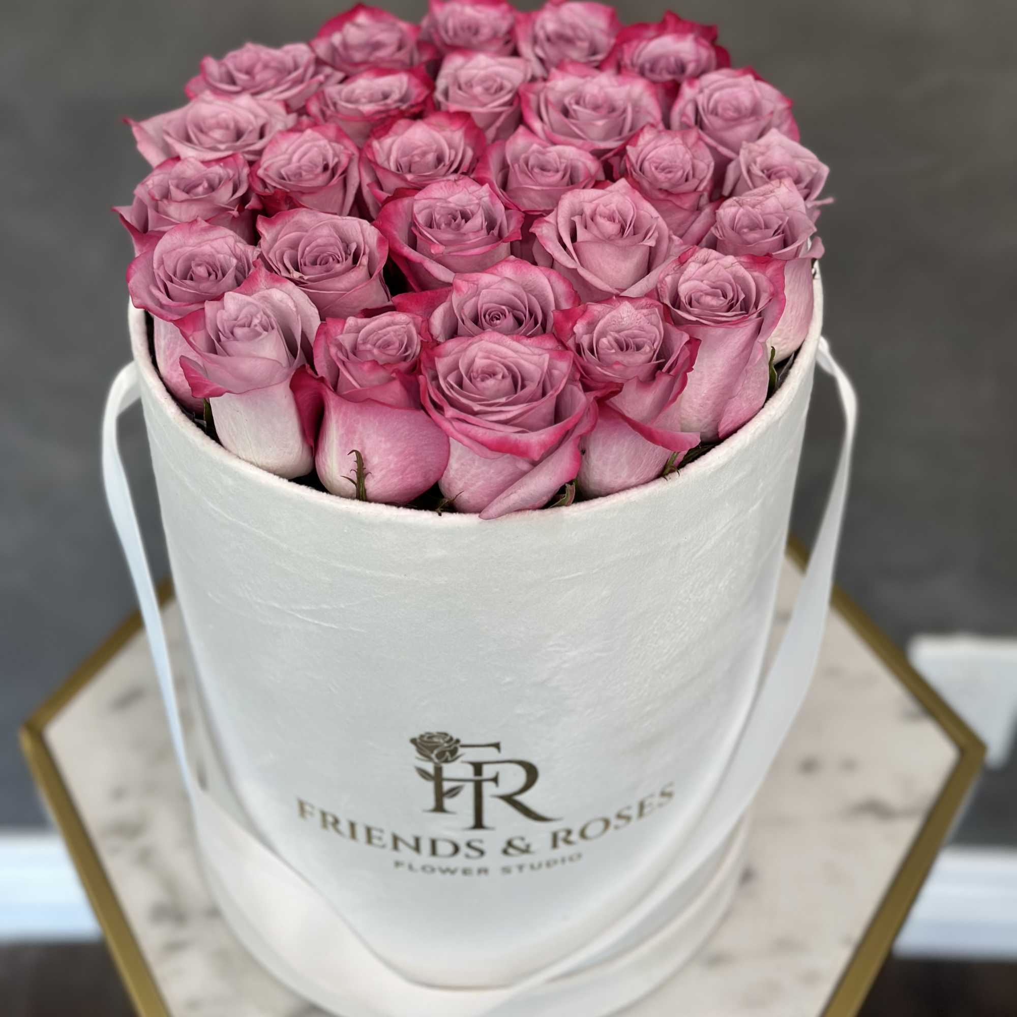 Pink roses arranged in a white round hat box