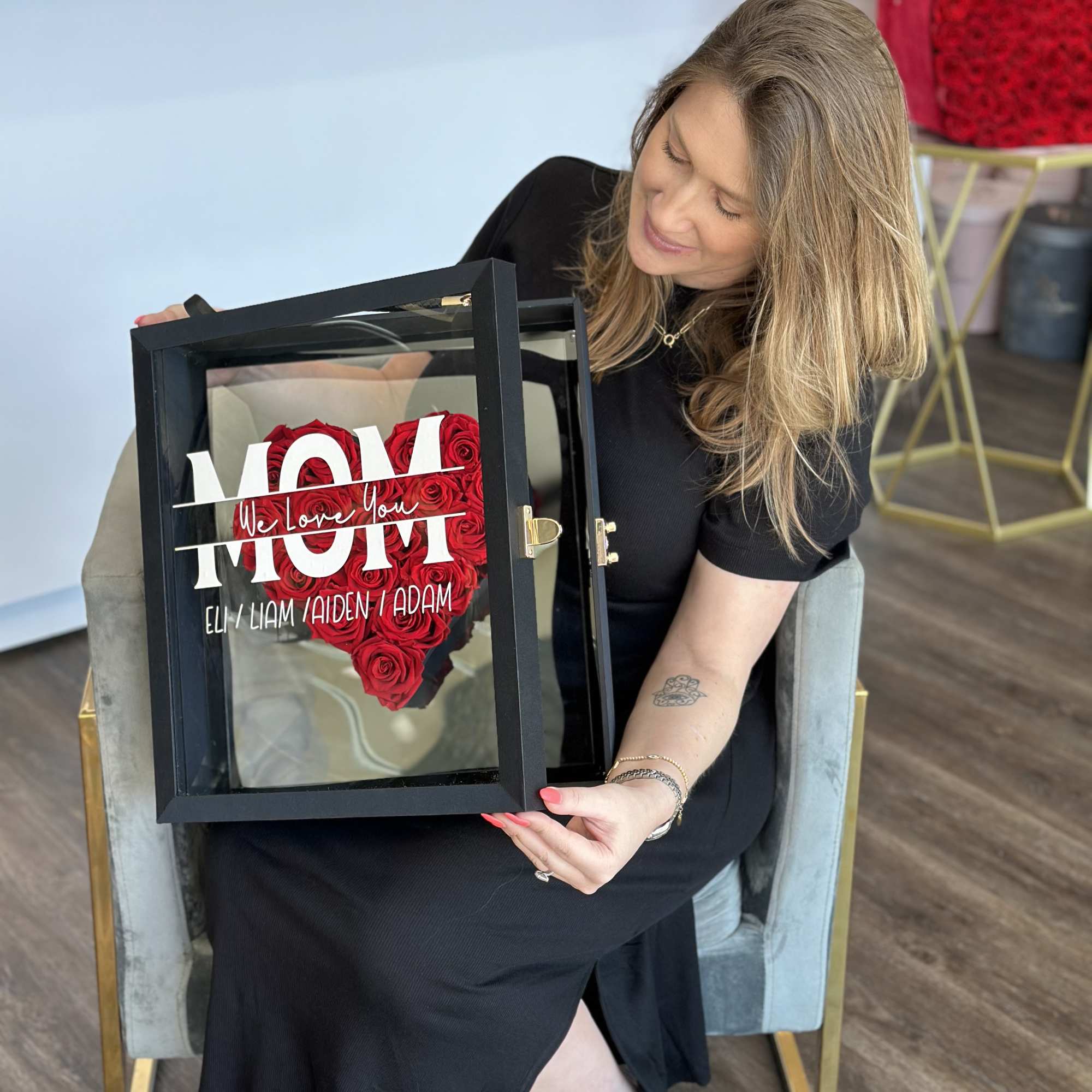 Woman holding a black display box with red roses arranged as a heart