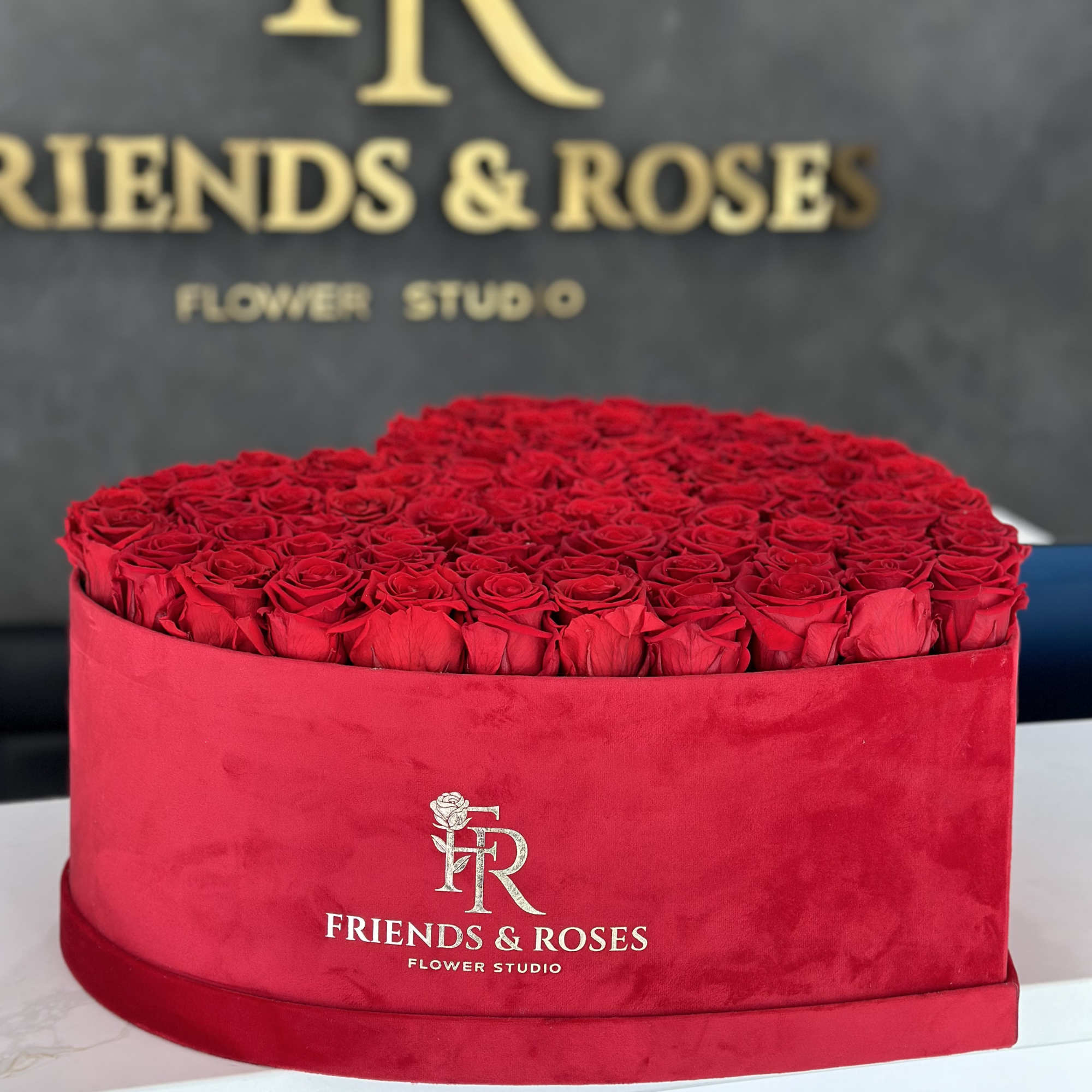 Round box filled with red roses and wrapped in red velvet