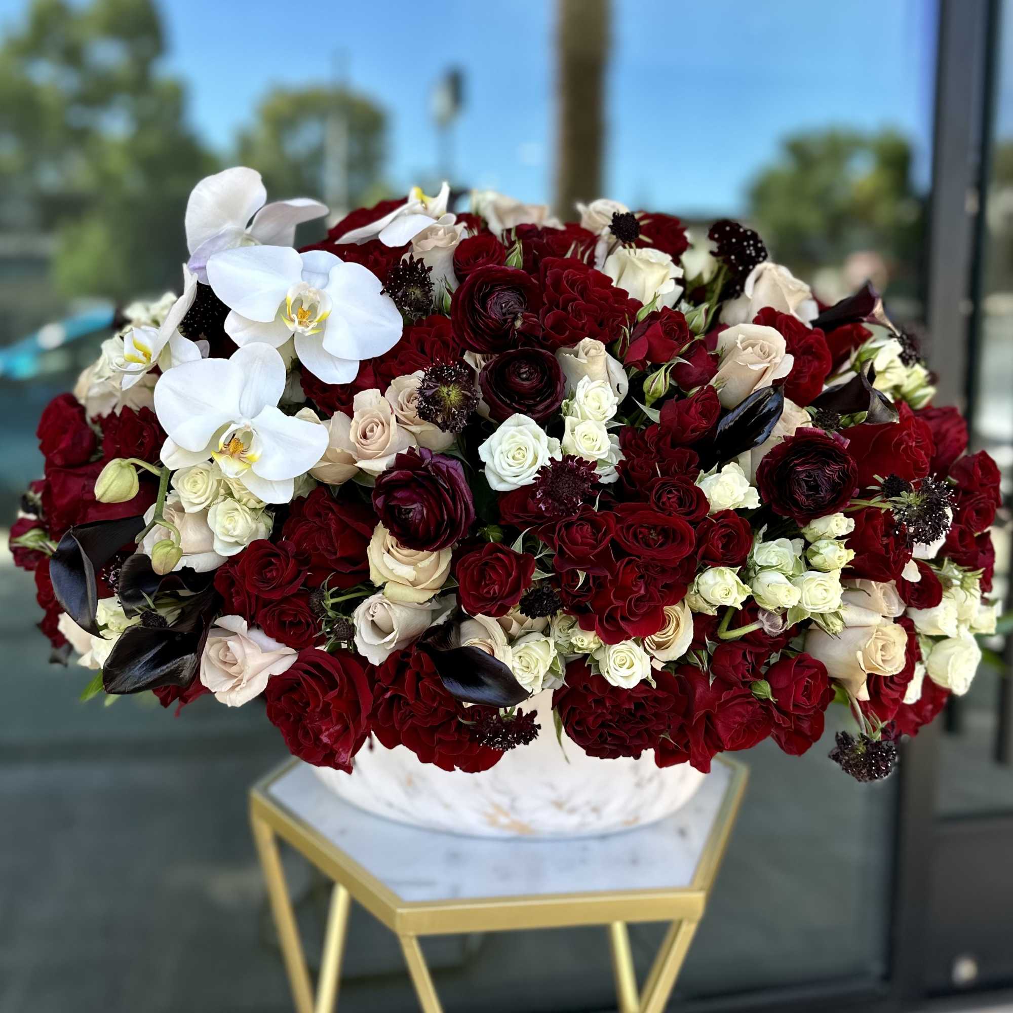Large bouquet of red and white roses with white orchids in a white vase