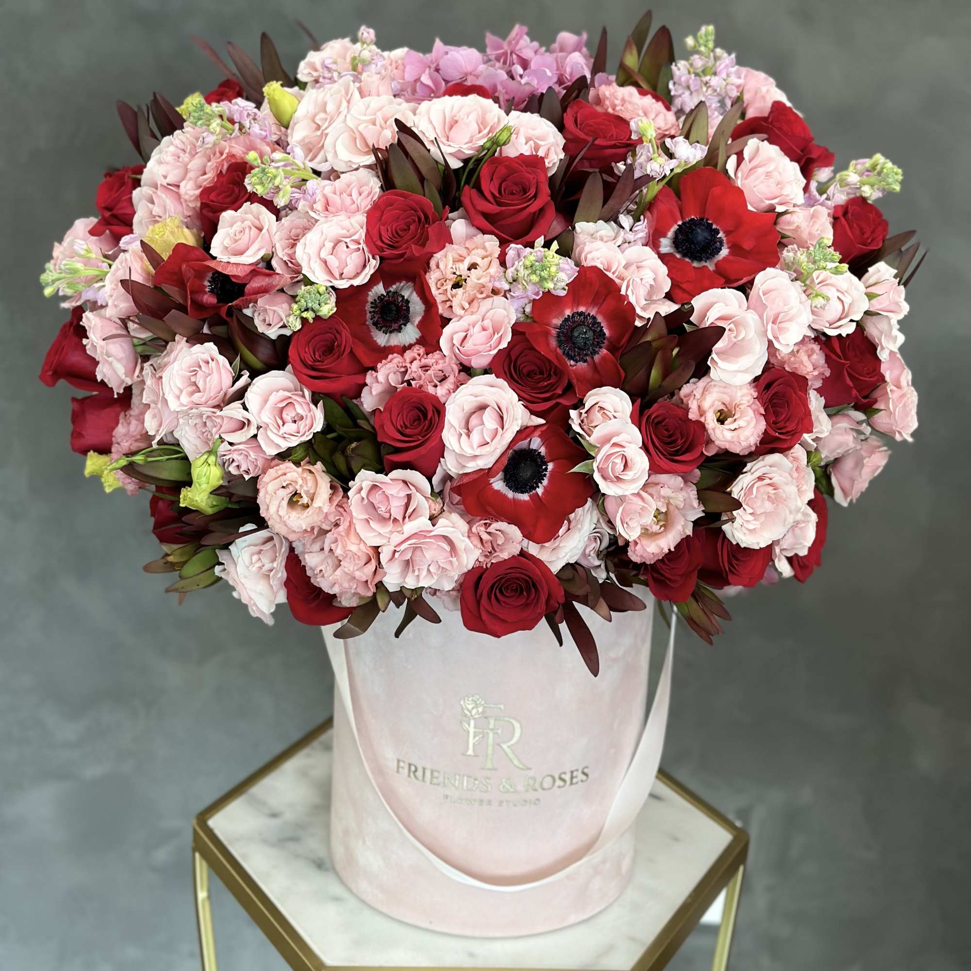 Bouquet of red and blush roses in a pink hatbox