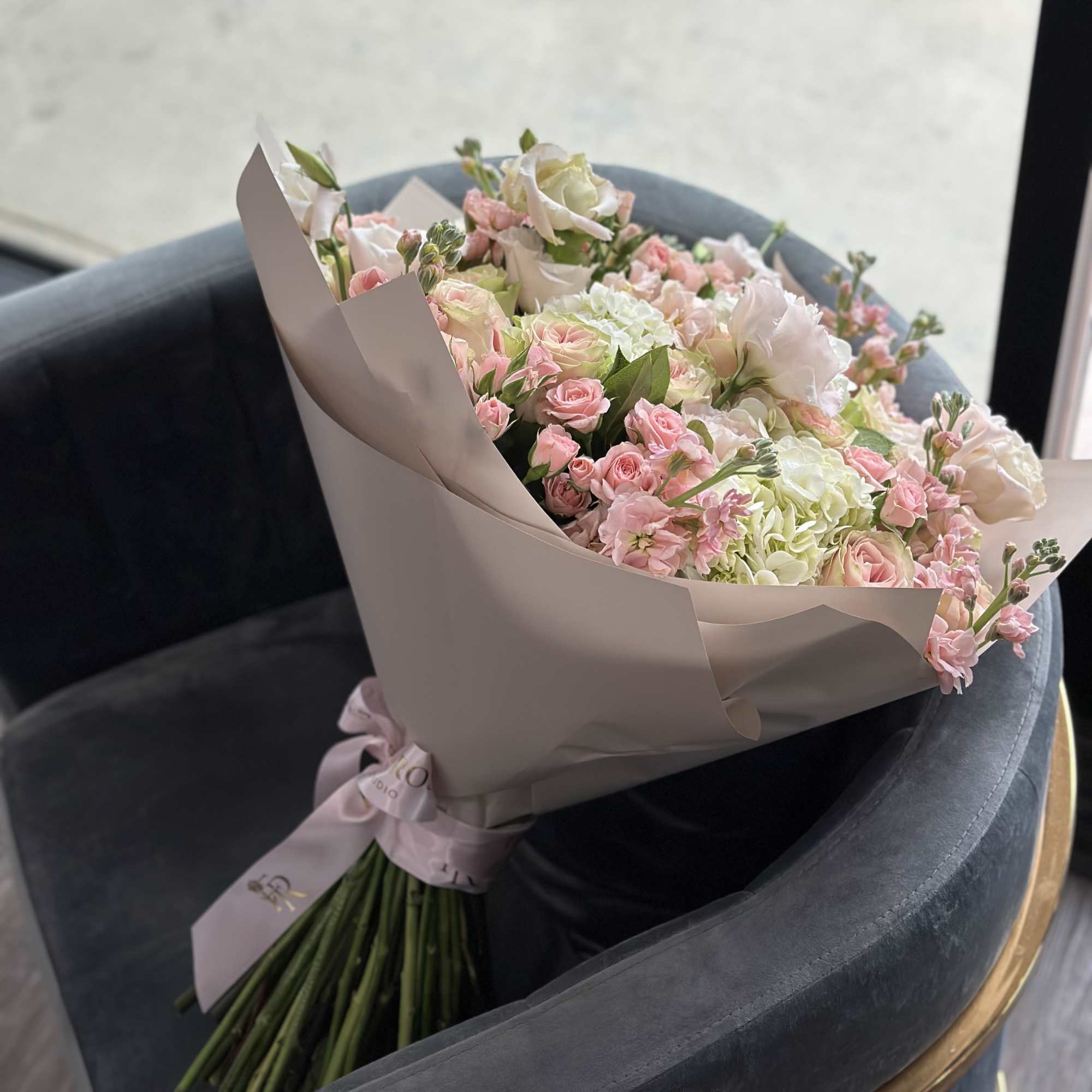 Bouquet of pink and white roses with pale hydrangeas wrapped in blush paper