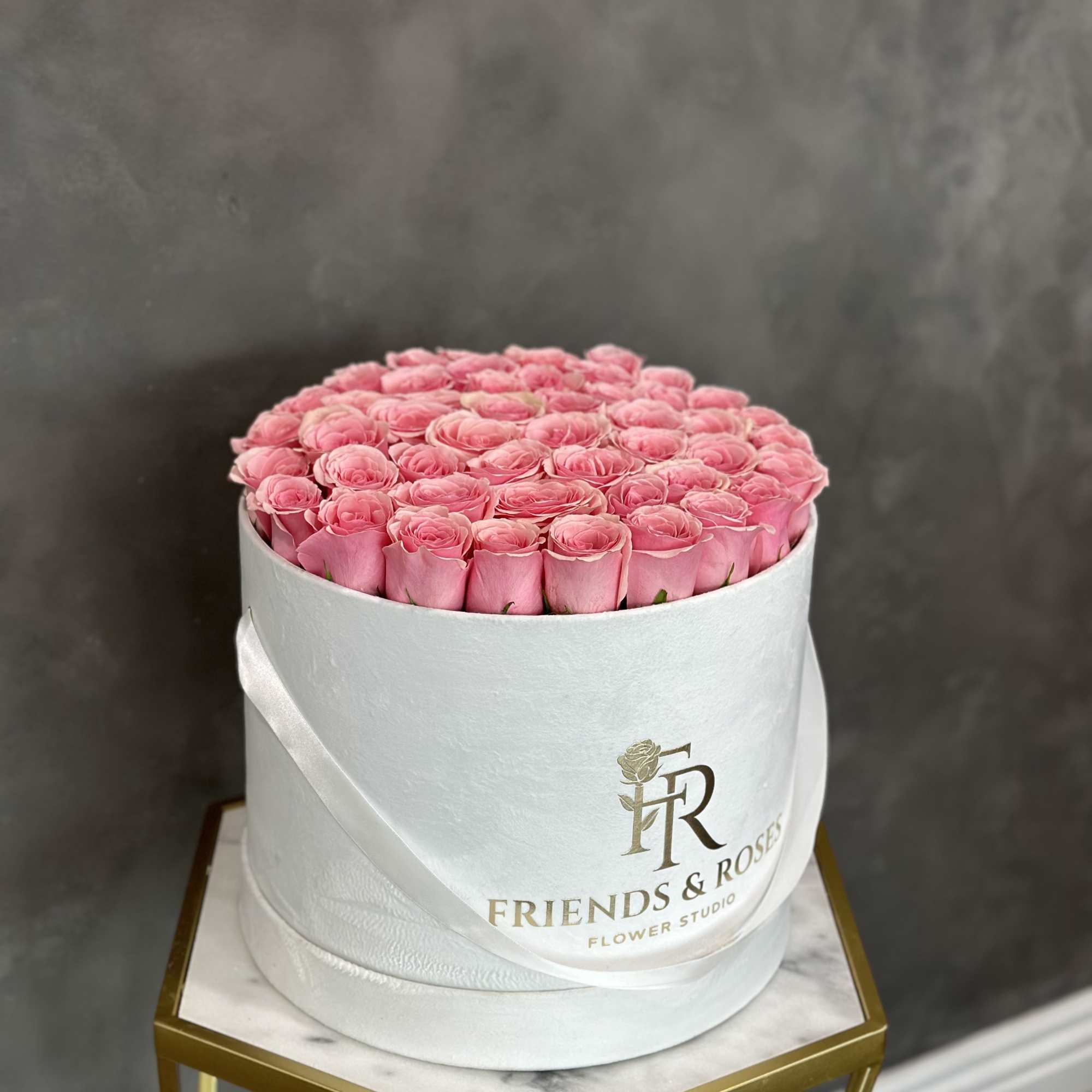 Round box of pink roses with a satin ribbon