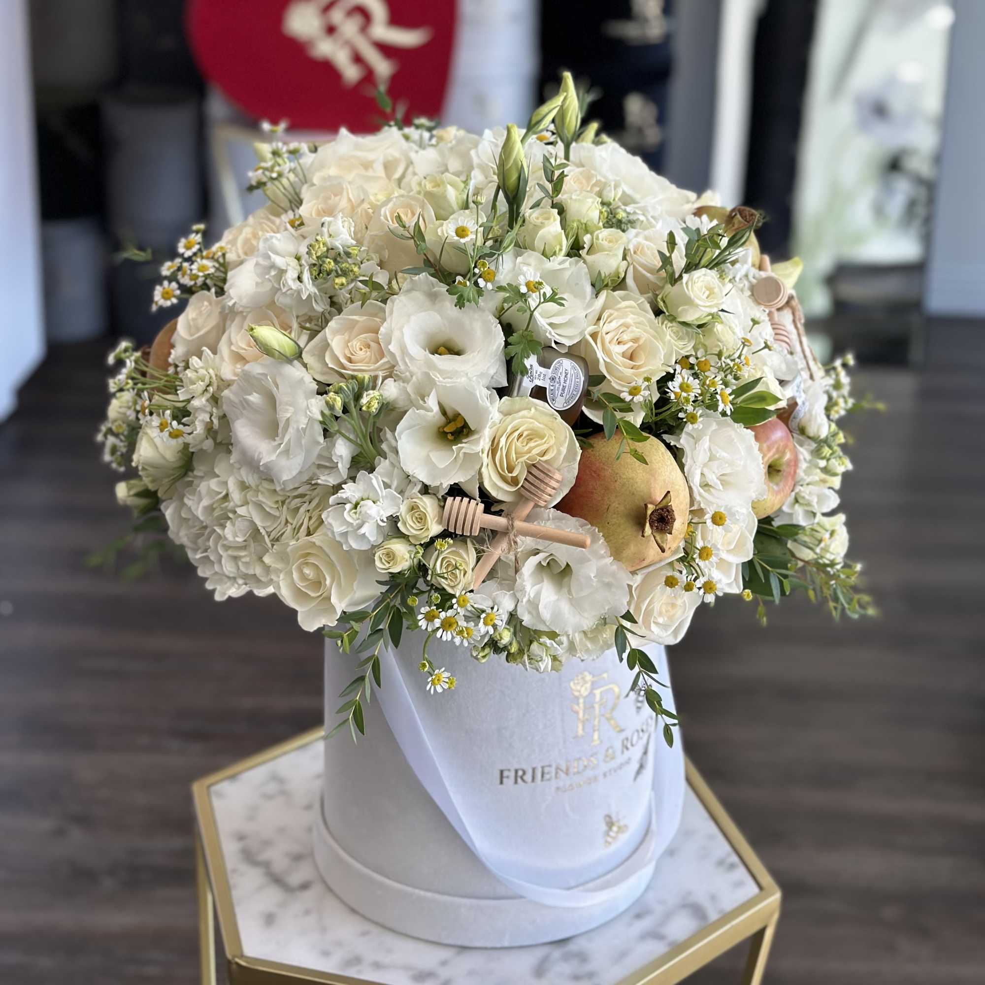 White floral arrangement in a round hatbox with pears and small daisies