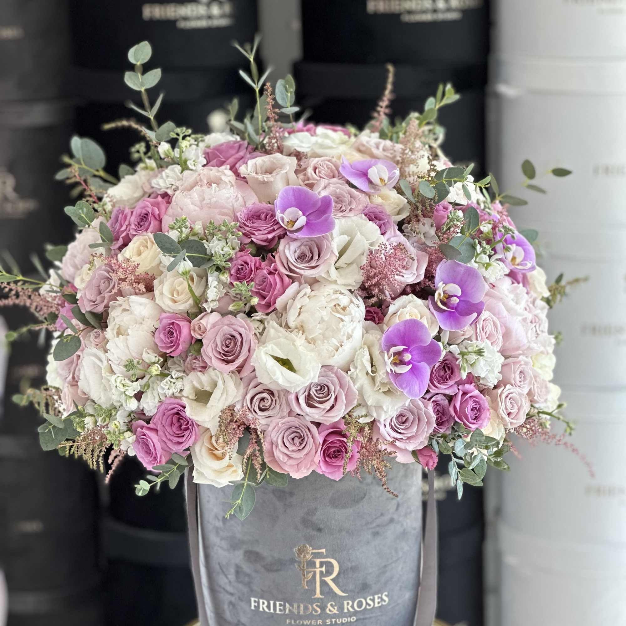 Large pink and white rose bouquet in a gray hatbox with purple orchids