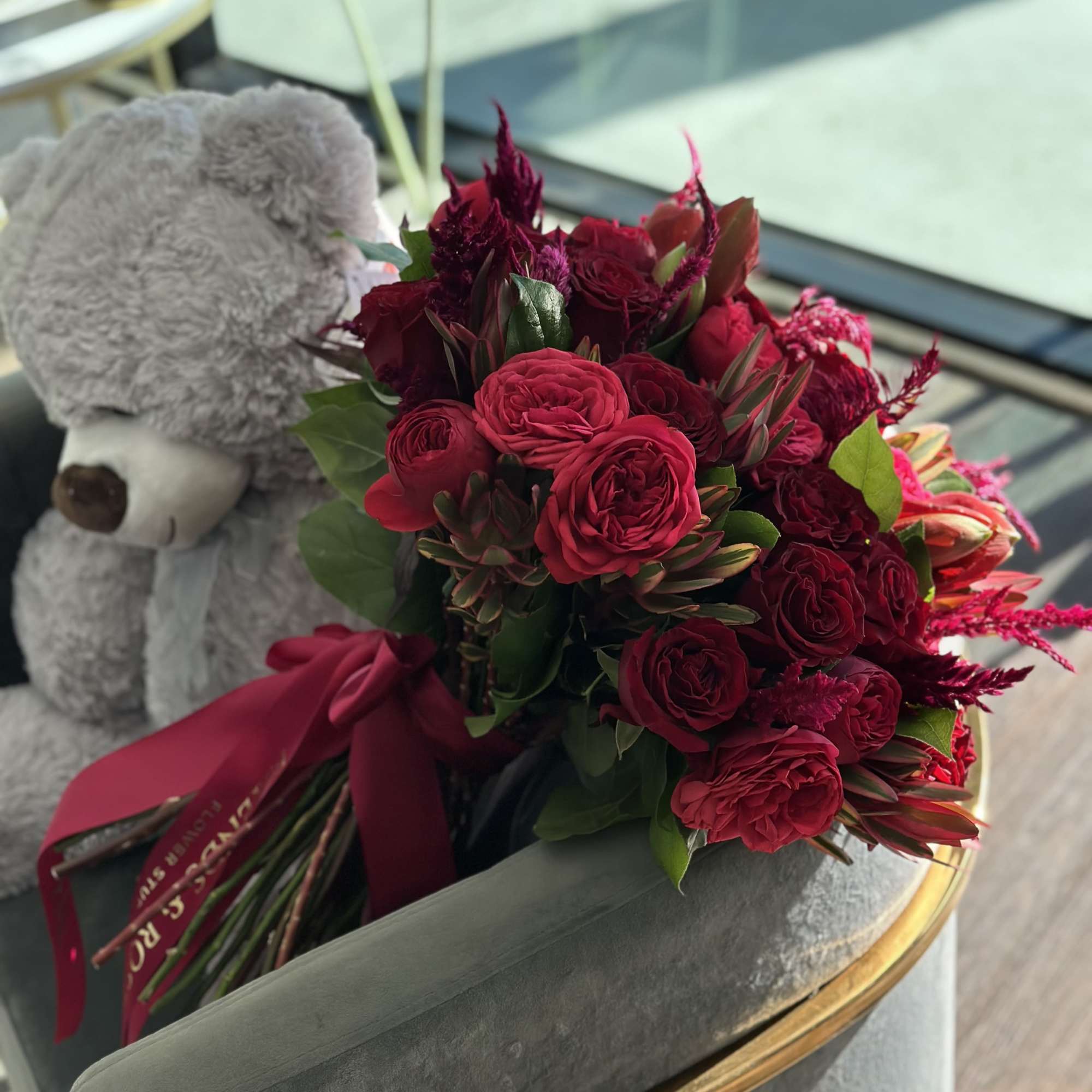 Bouquet of deep red roses with a gray teddy bear