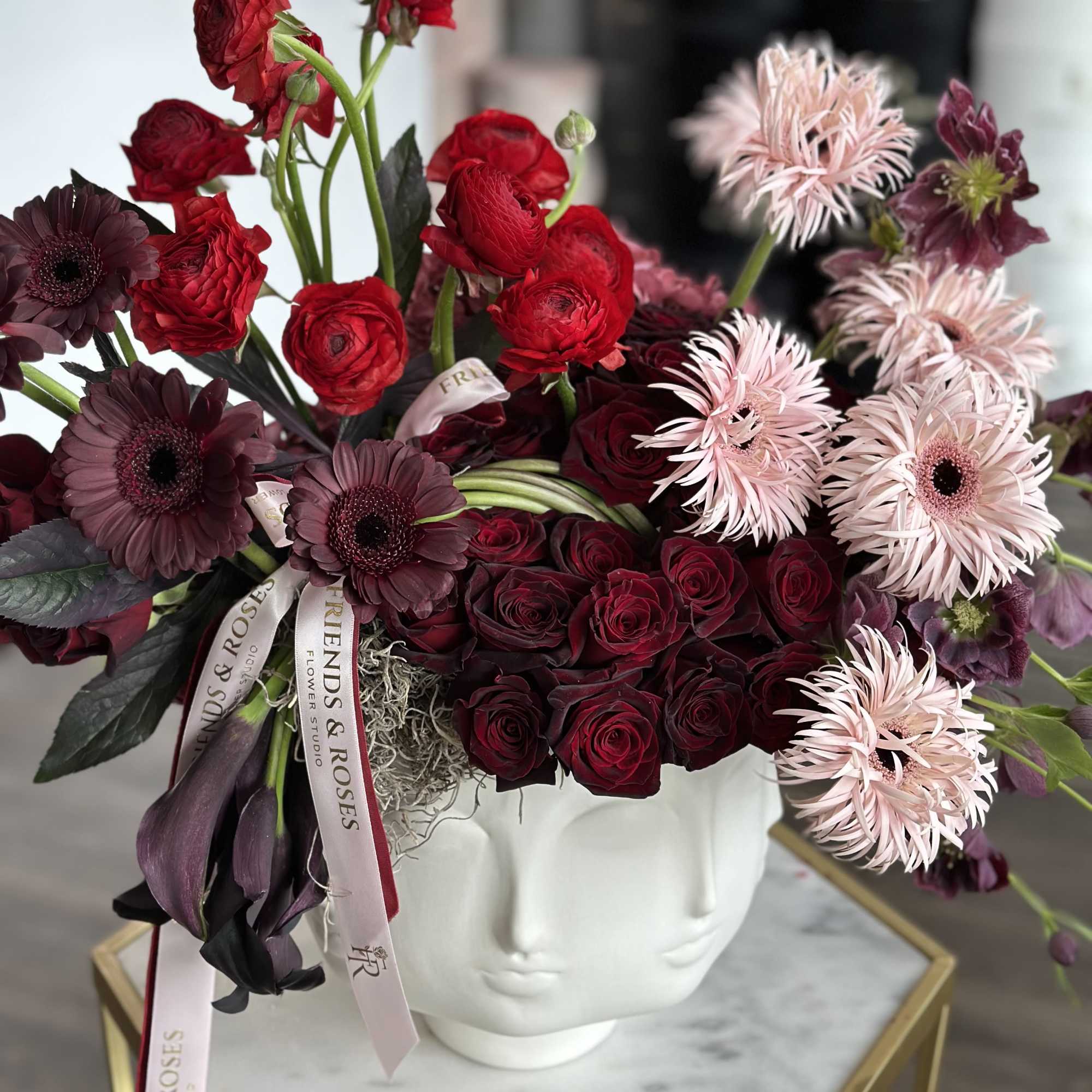 Bouquet of red and burgundy flowers in a white face-shaped vase