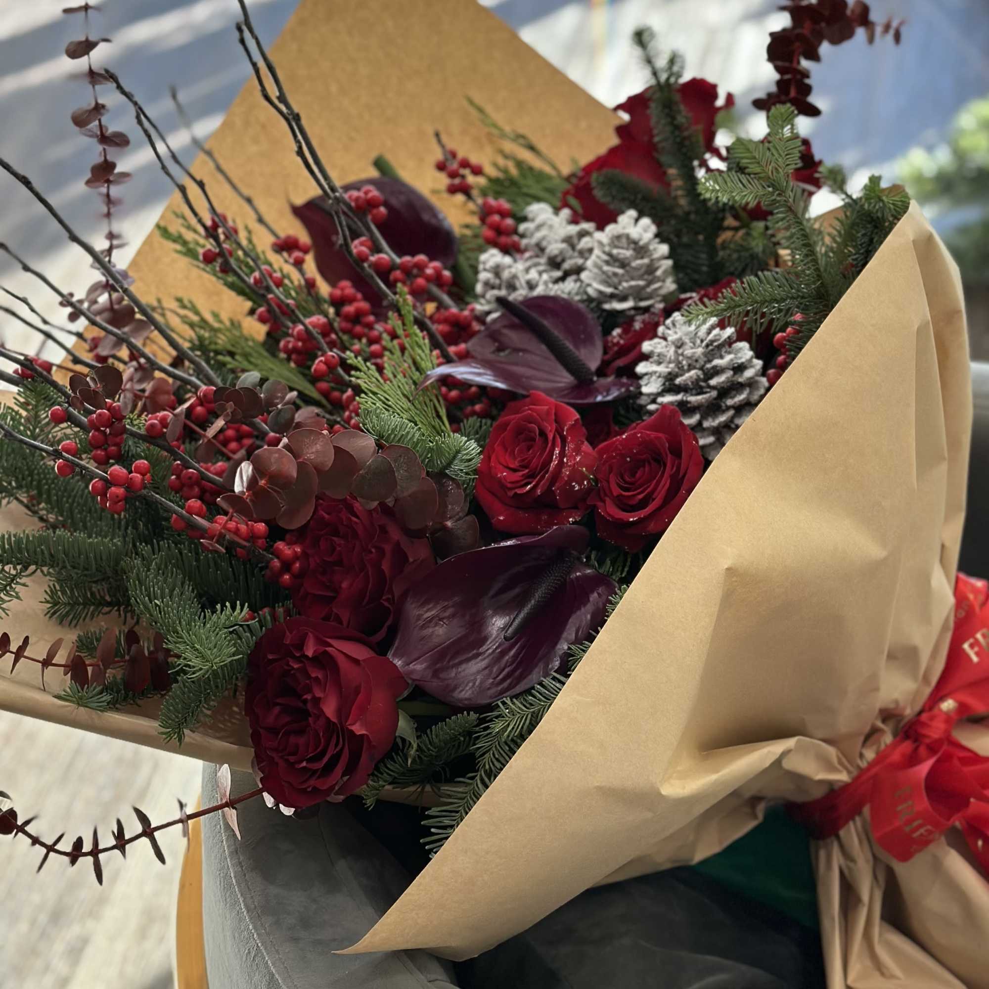 Bouquet of red roses and dark burgundy flowers wrapped in kraft paper