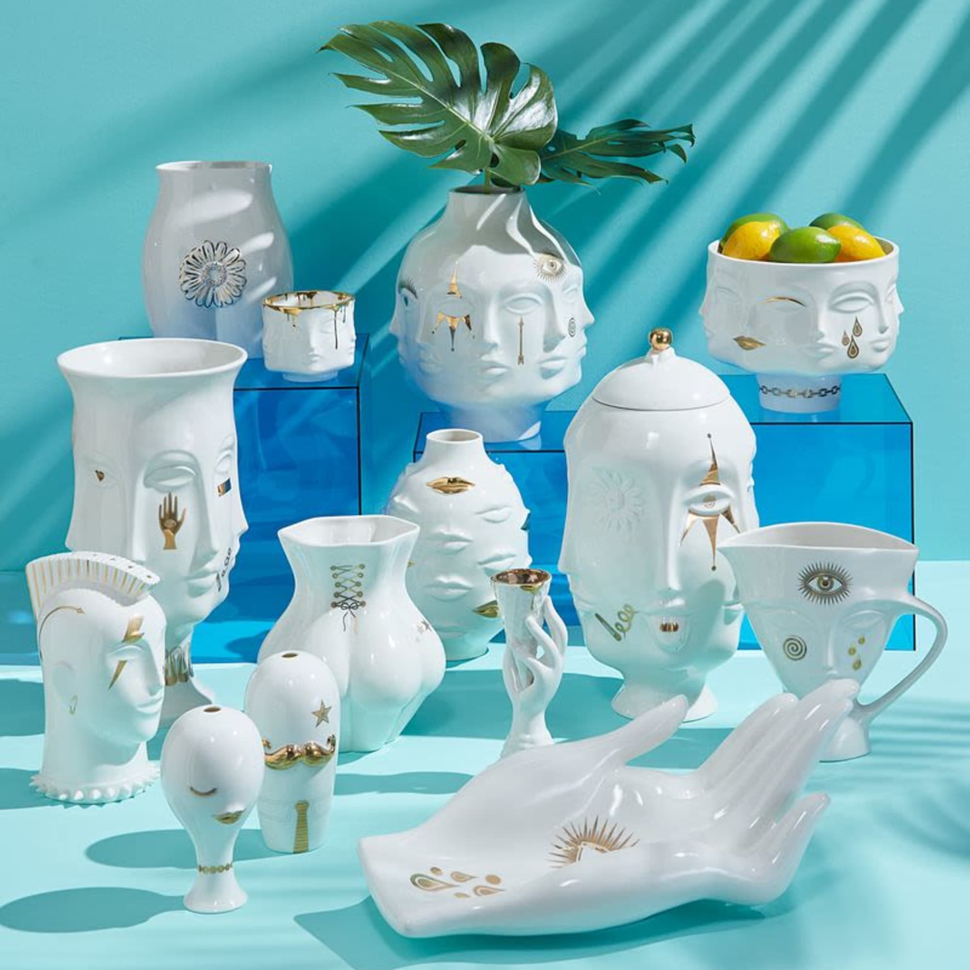 Assorted white ceramic face-shaped vases and bowls on blue blocks