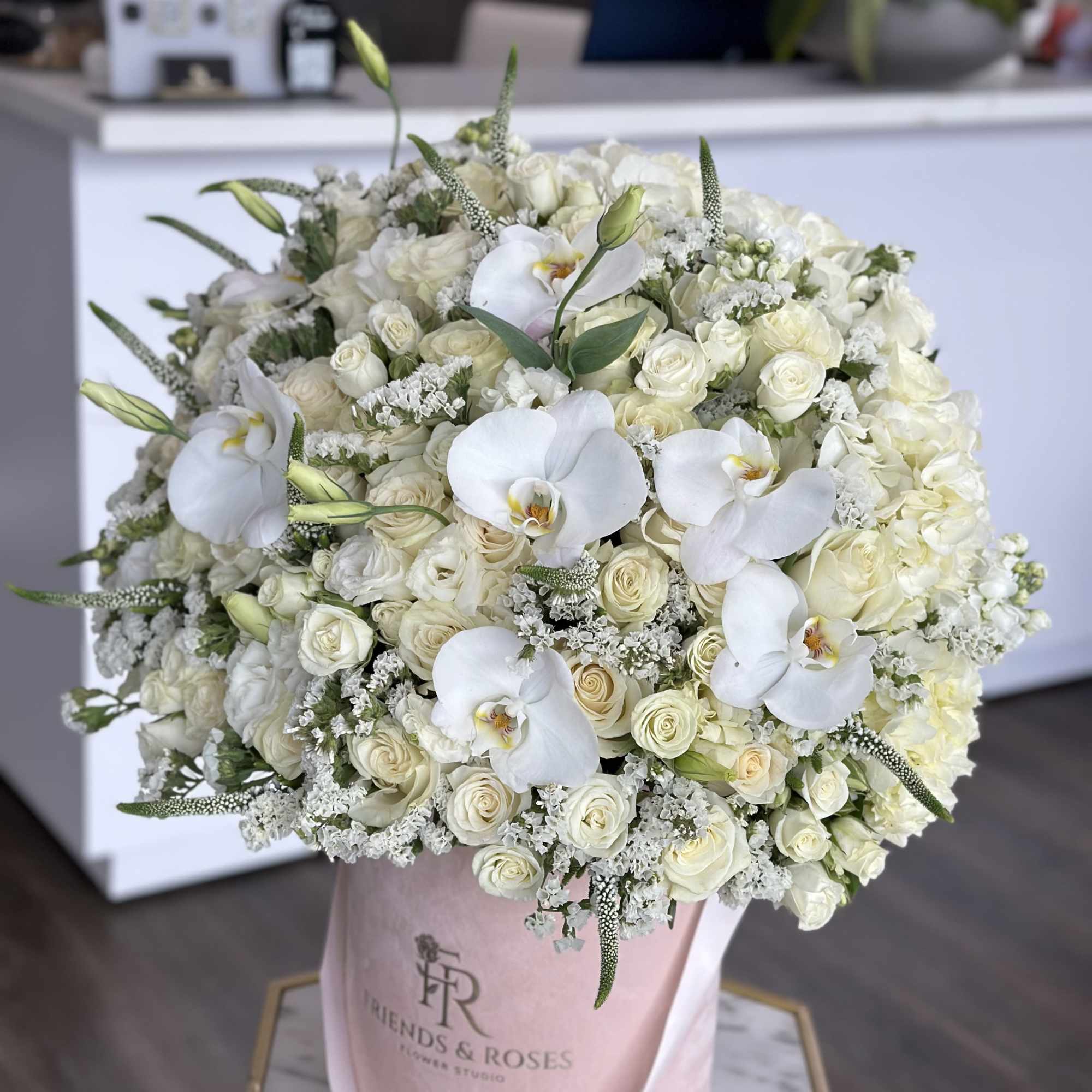 White rose and orchid bouquet in a pink hat box