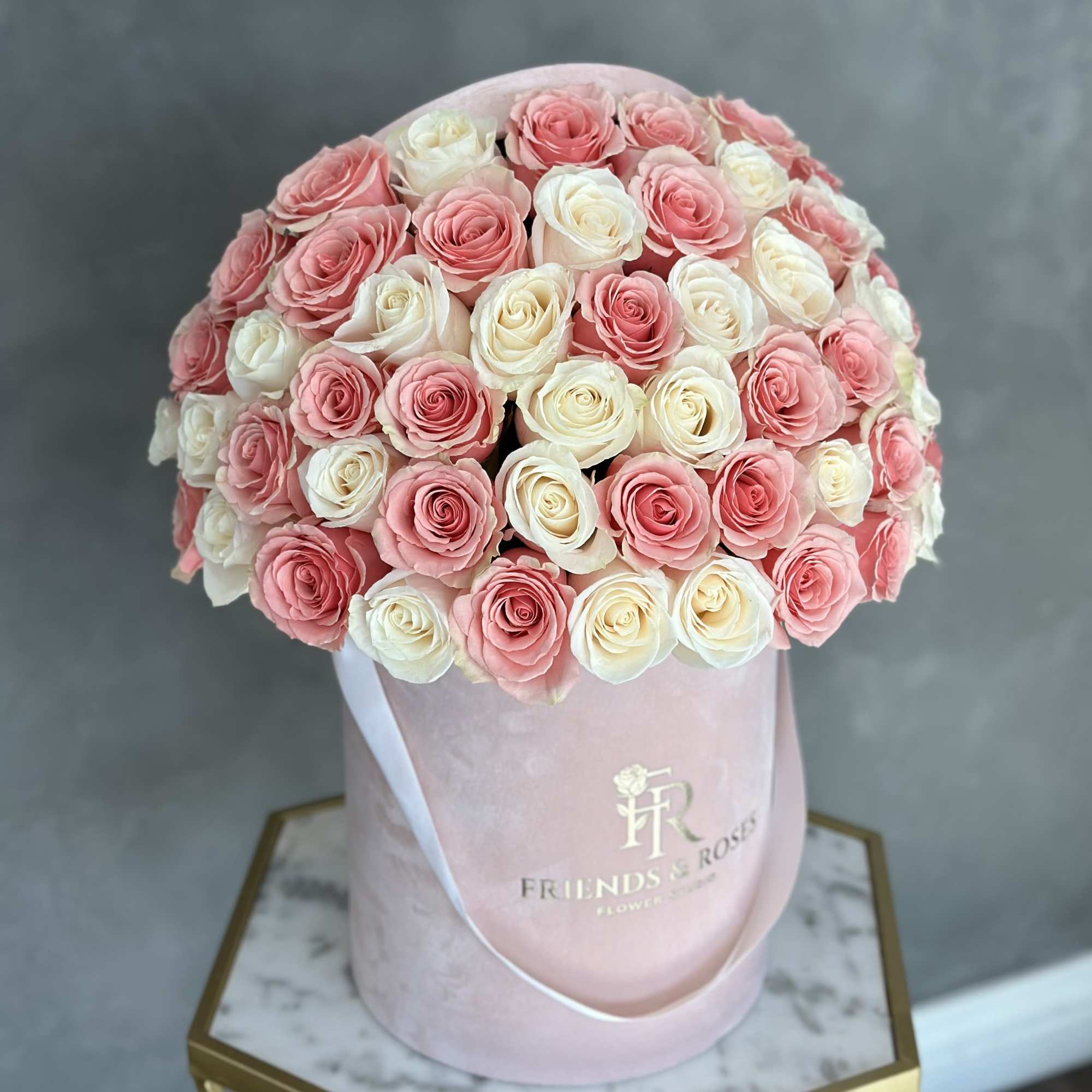 Pink and white roses arranged in a round pink box