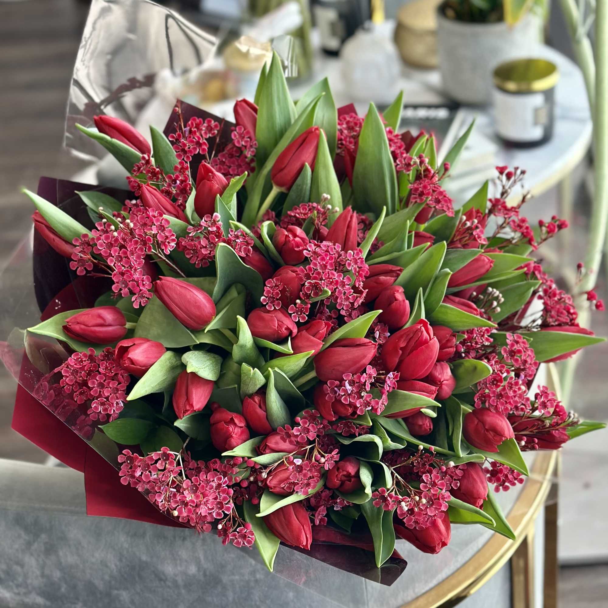 Bouquet of red tulips with pink filler flowers and green leaves