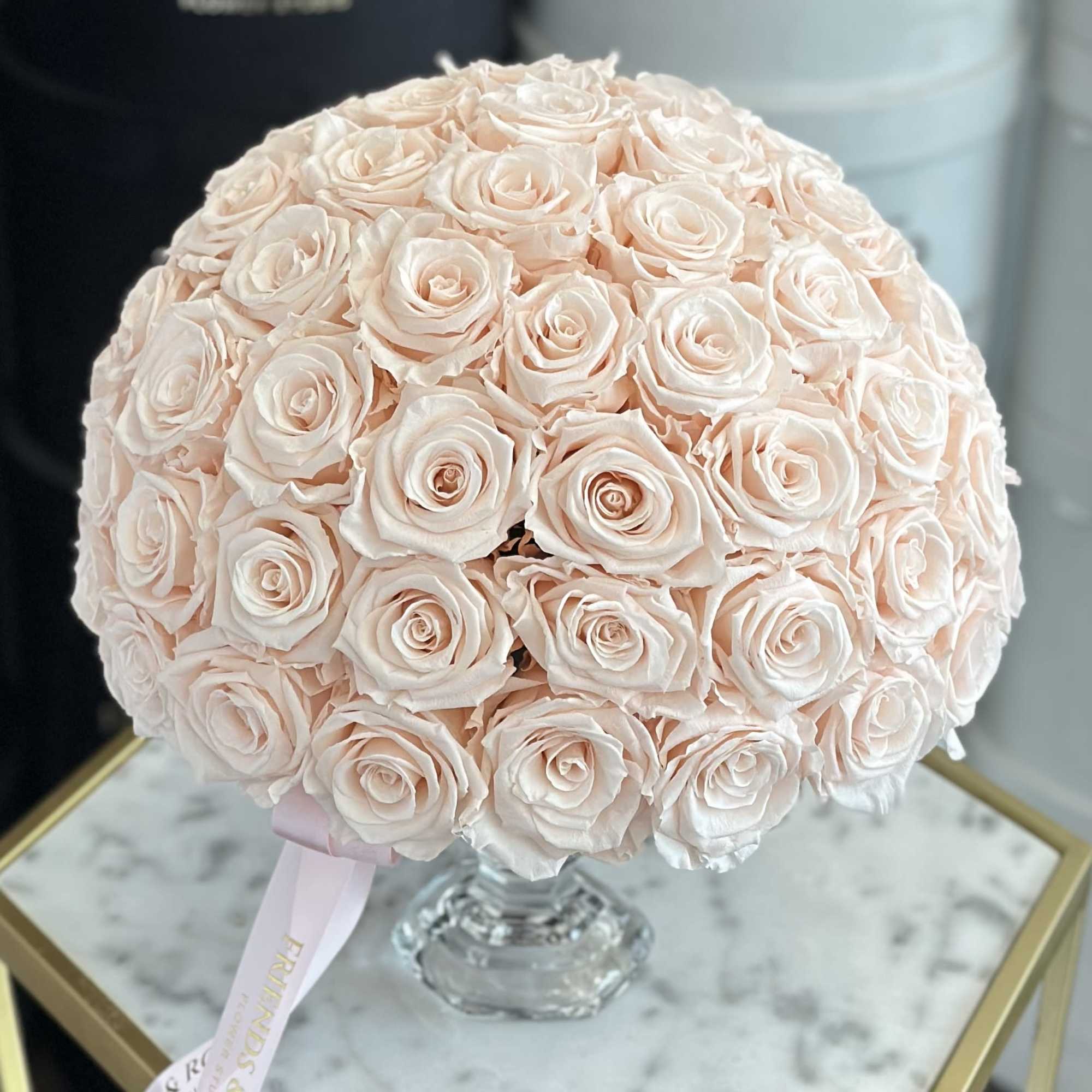 Round bouquet of pale blush roses in a clear glass vase