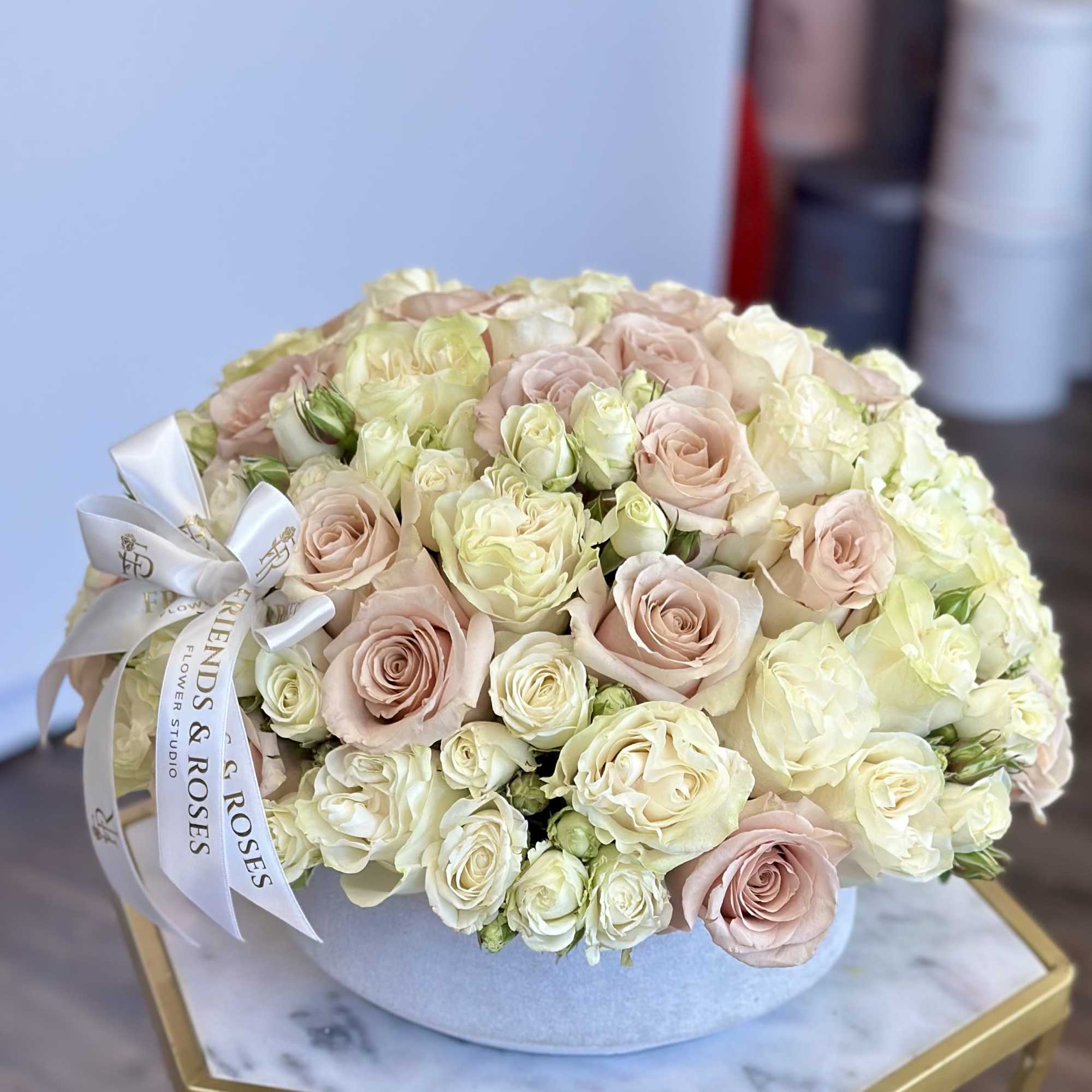 Round bouquet of blush and cream roses in a pale box with a ribbon