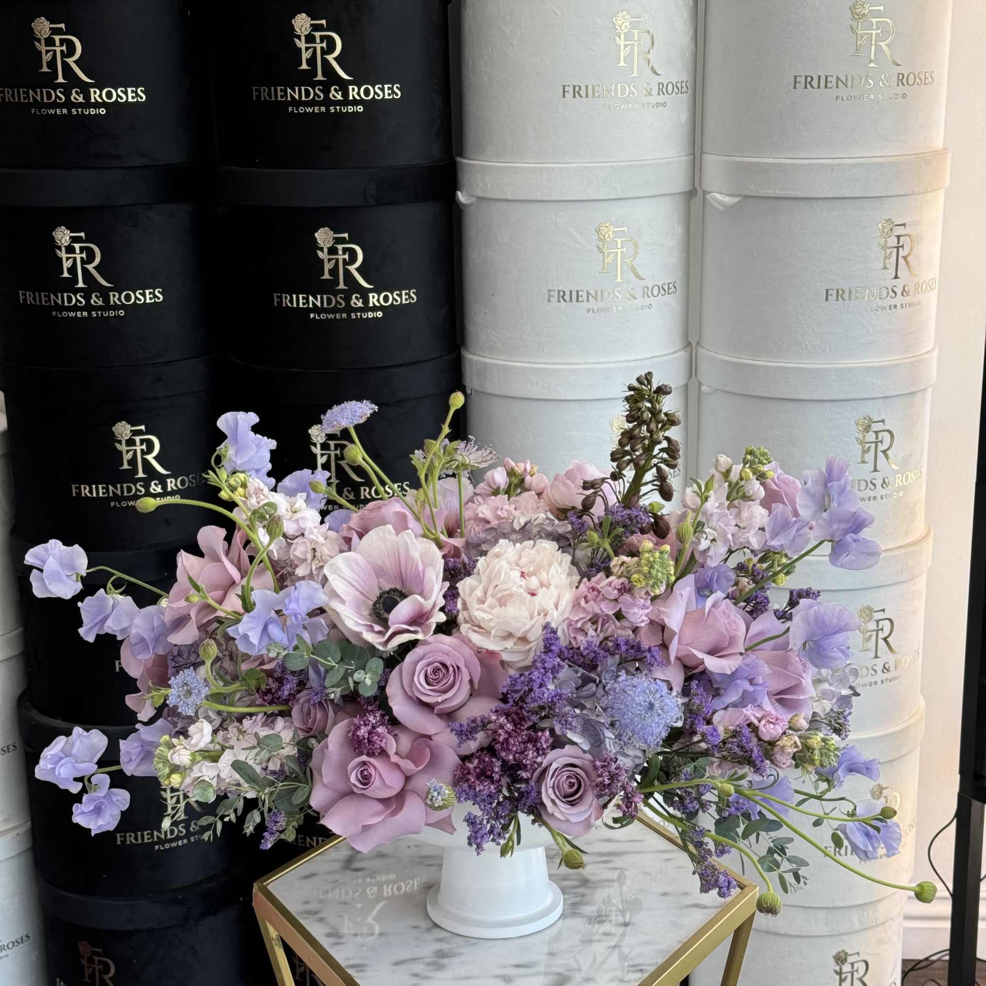 Lavender and pink floral arrangement in a white pedestal vase