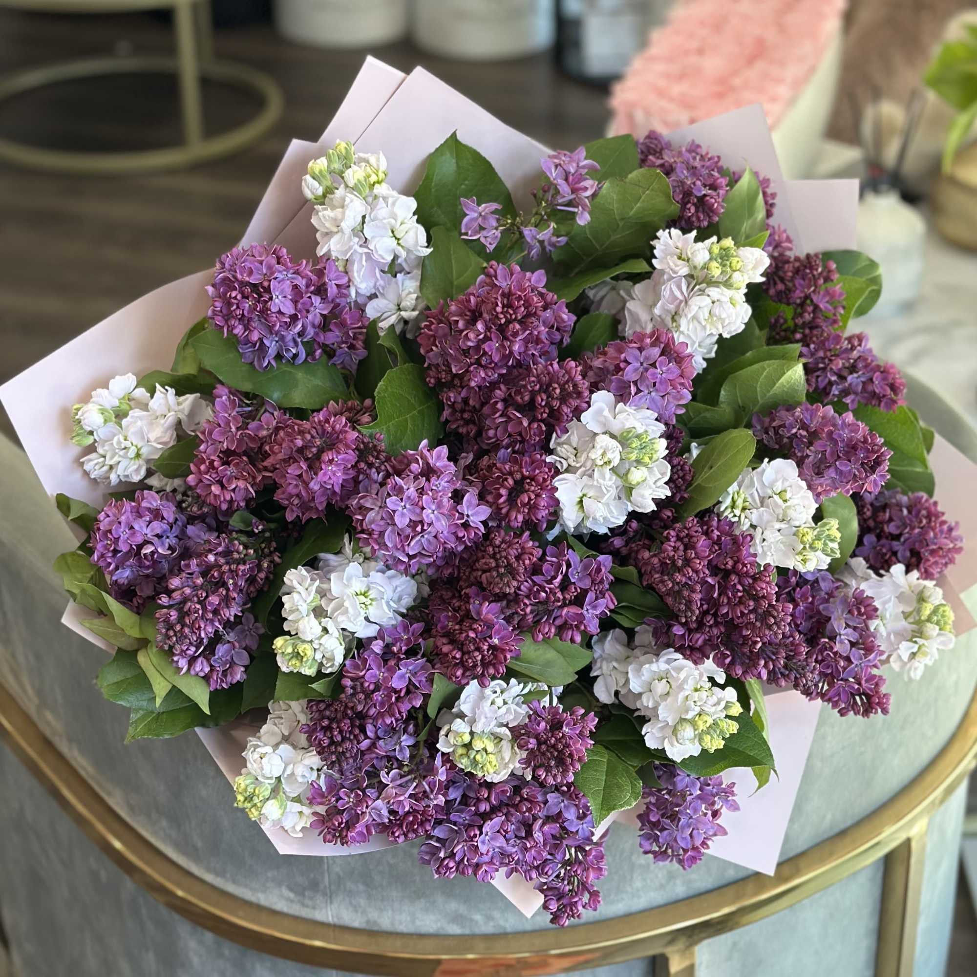 Bouquet of purple and white lilac blooms wrapped in pale paper