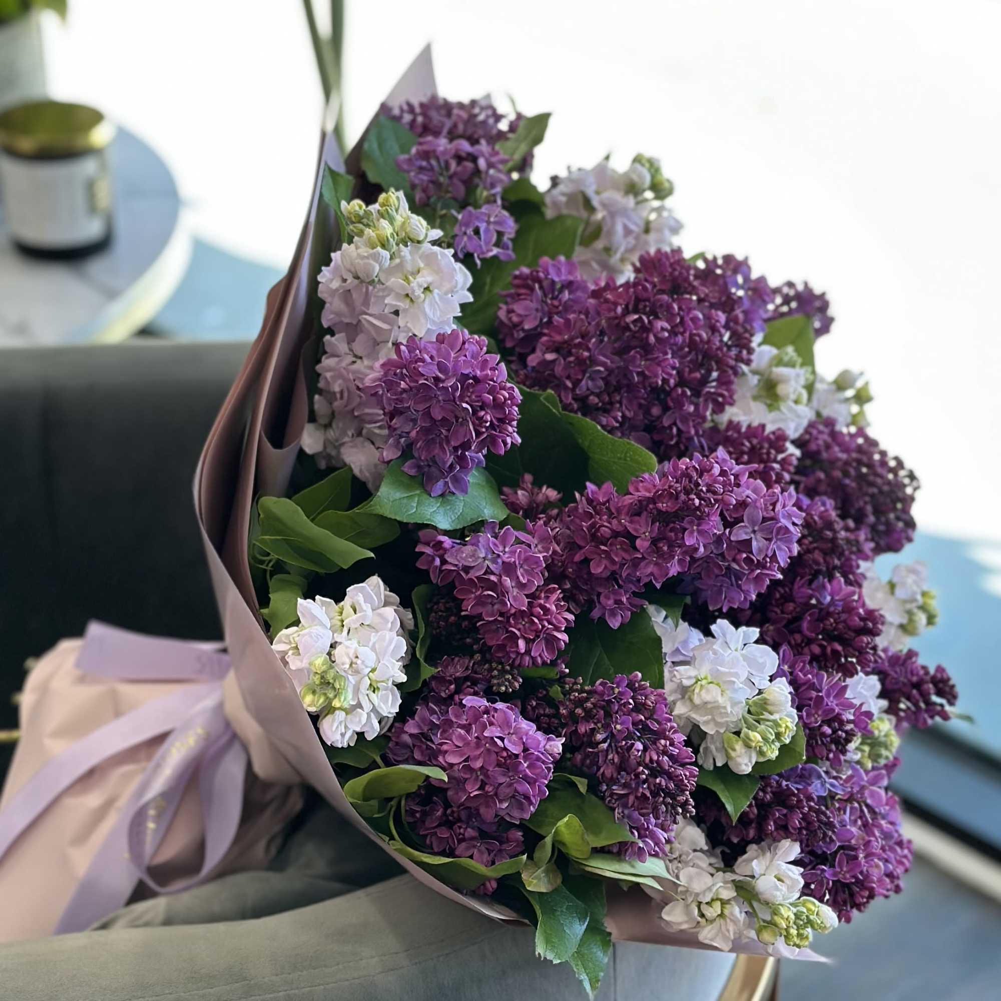 Bouquet of purple and white lilac flowers wrapped in mauve paper
