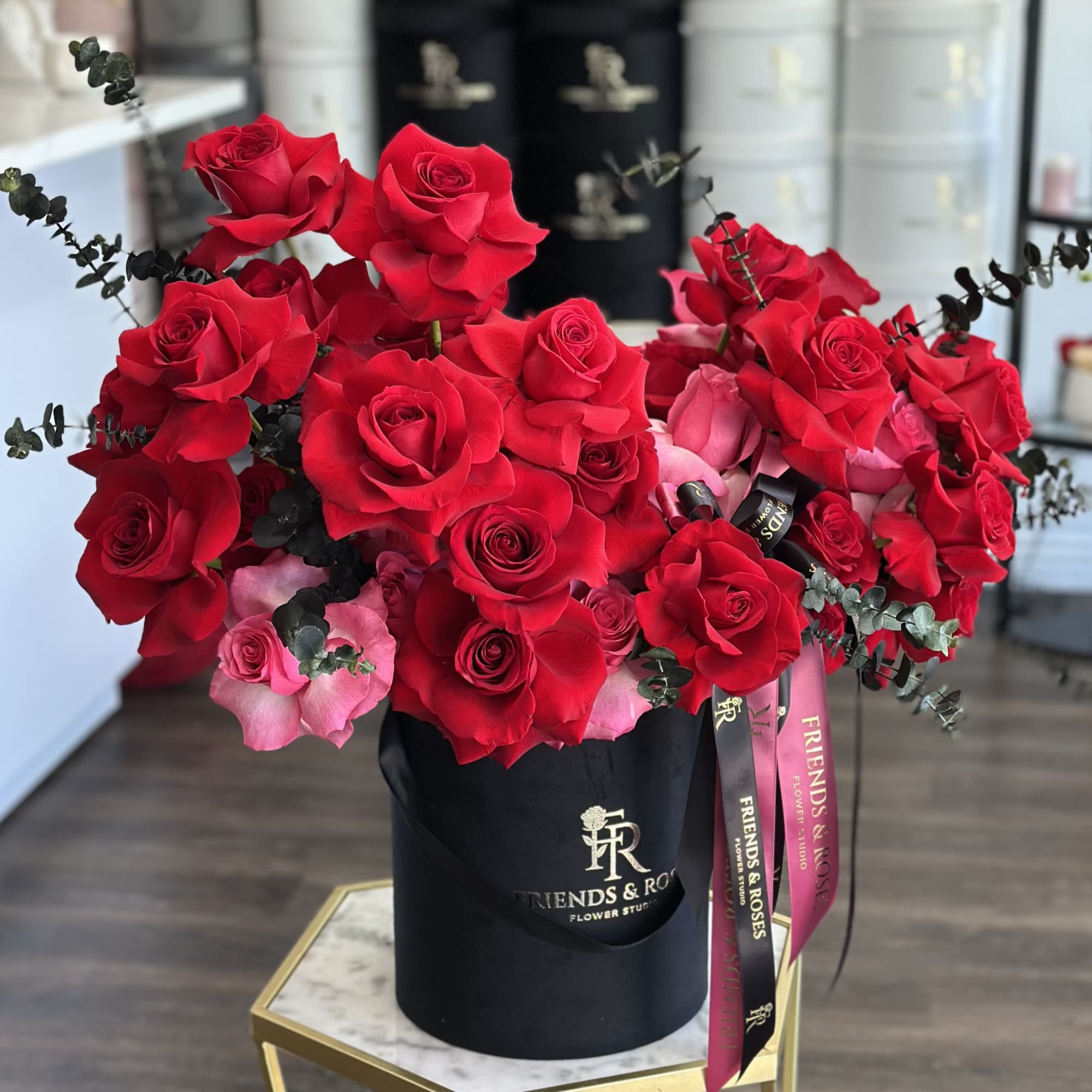 Large bouquet of red and pink roses in a black hat box