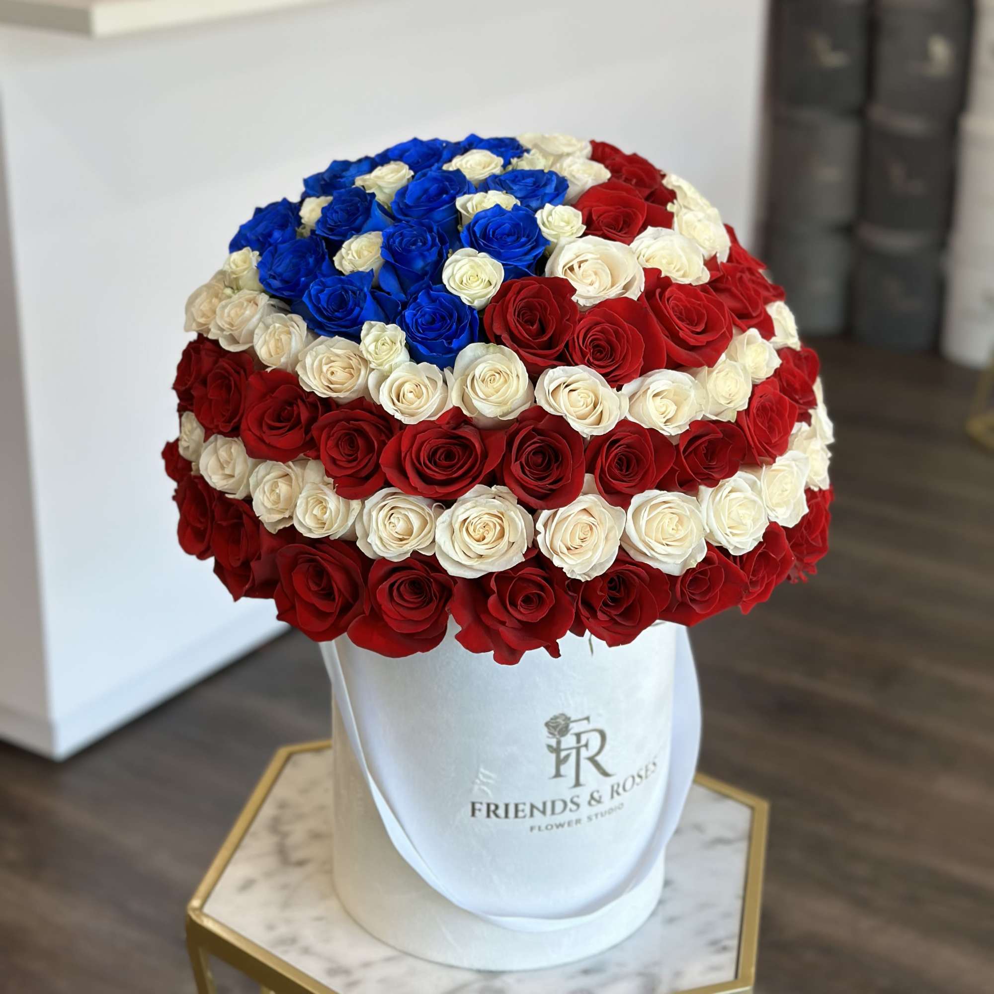 Round bouquet of red, white, and blue roses in a white hat box