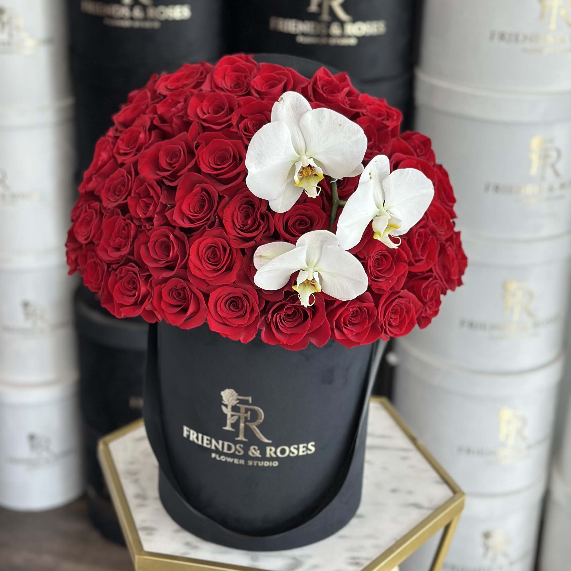 Red roses with white orchids in a black hat box