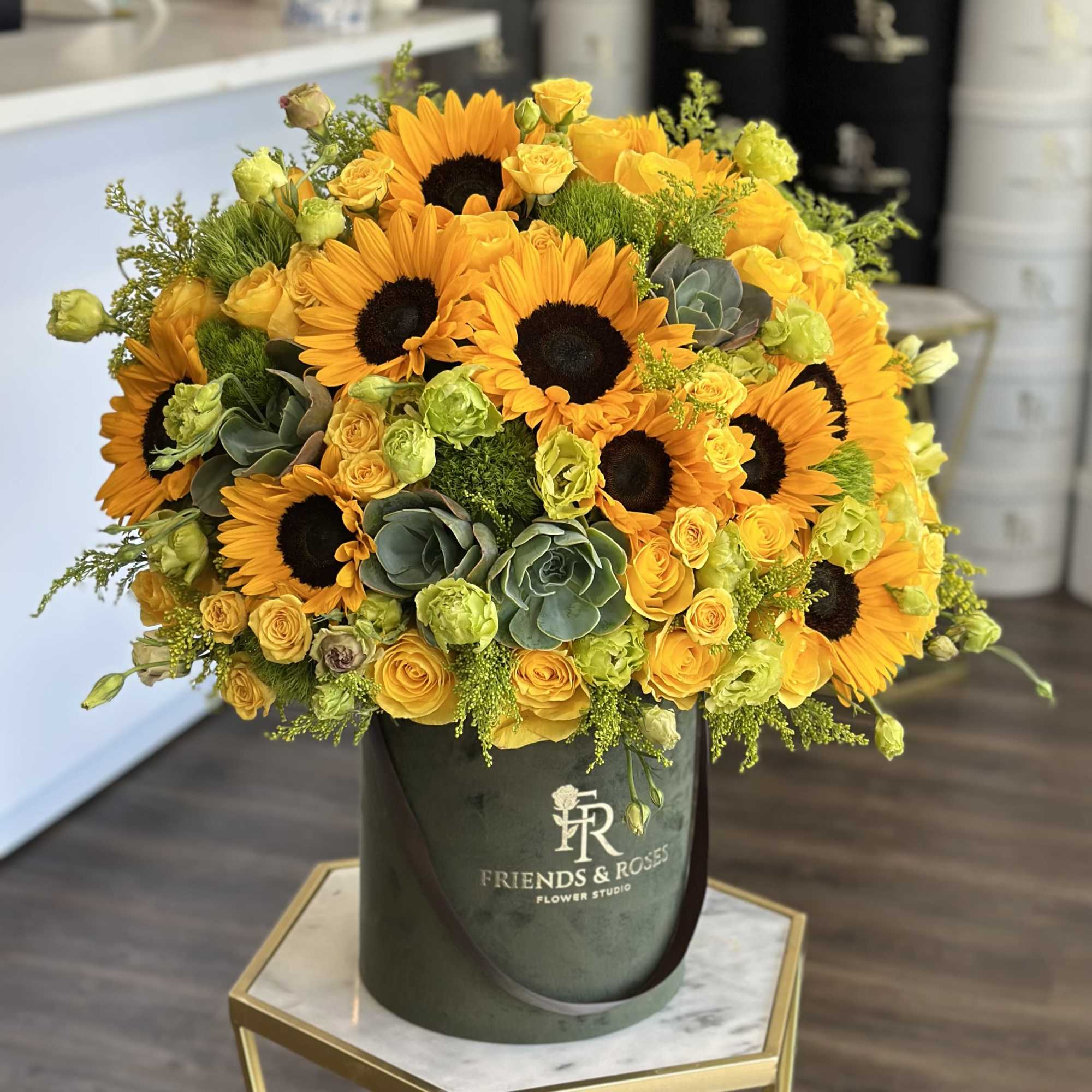 Sunflower and yellow rose arrangement in a dark green box
