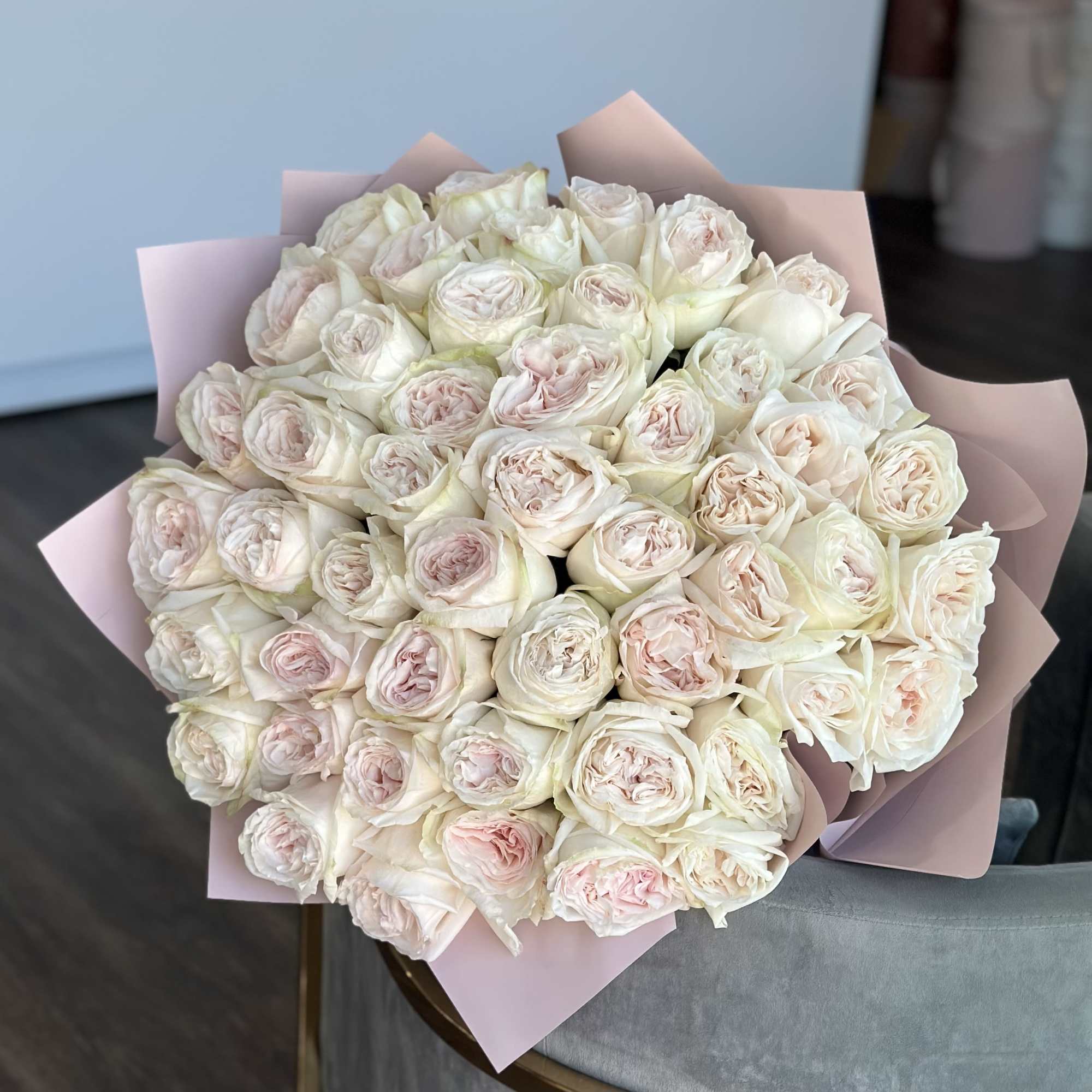 Bouquet of pale pink and white roses wrapped in blush paper