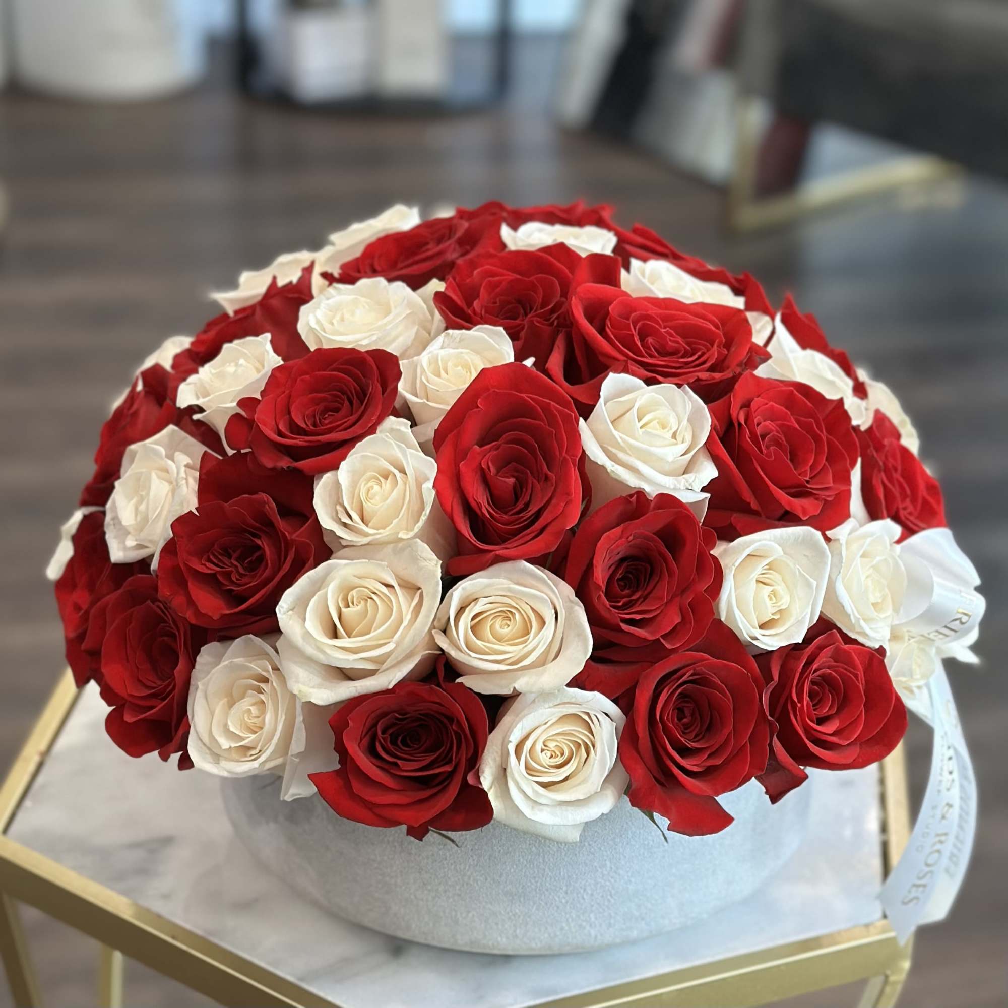 Round box arrangement of red and white roses
