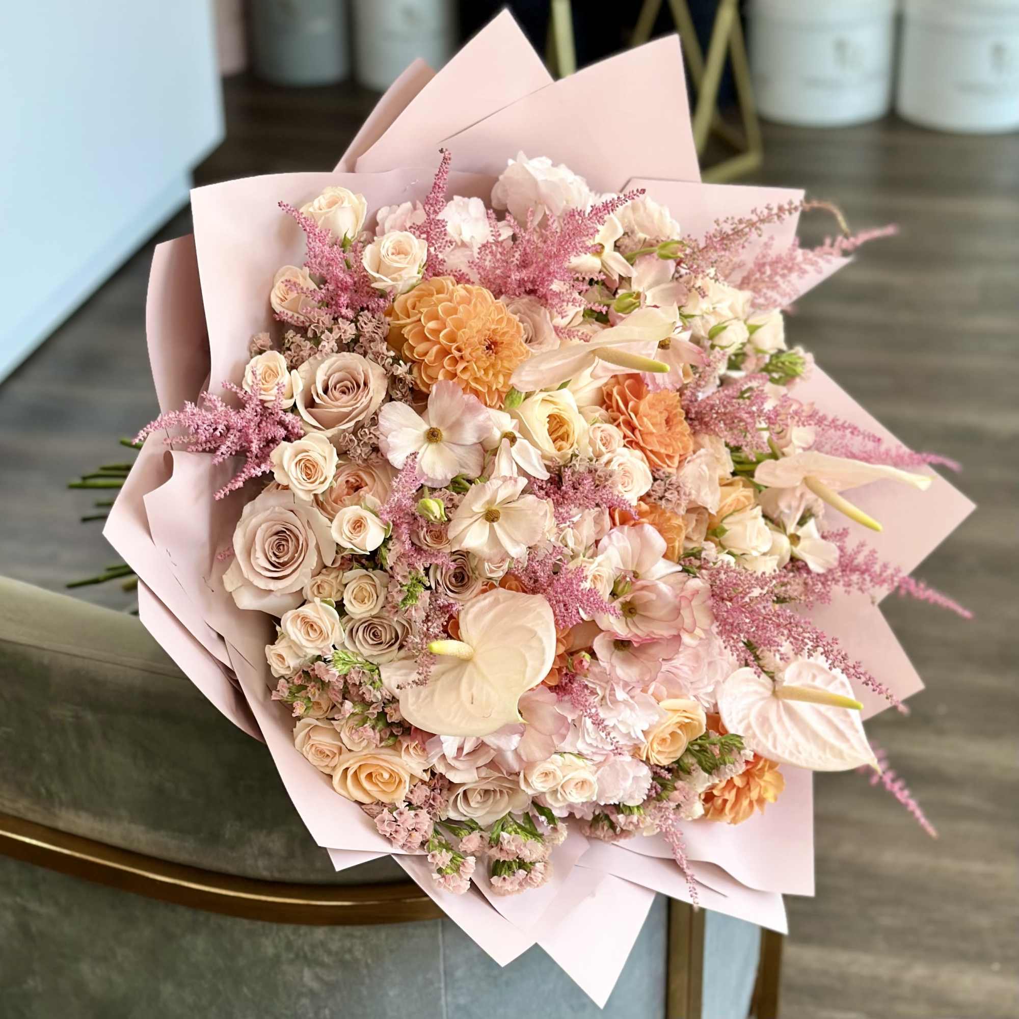 Large pastel bouquet of roses, anthuriums, and pink filler flowers wrapped in blush paper