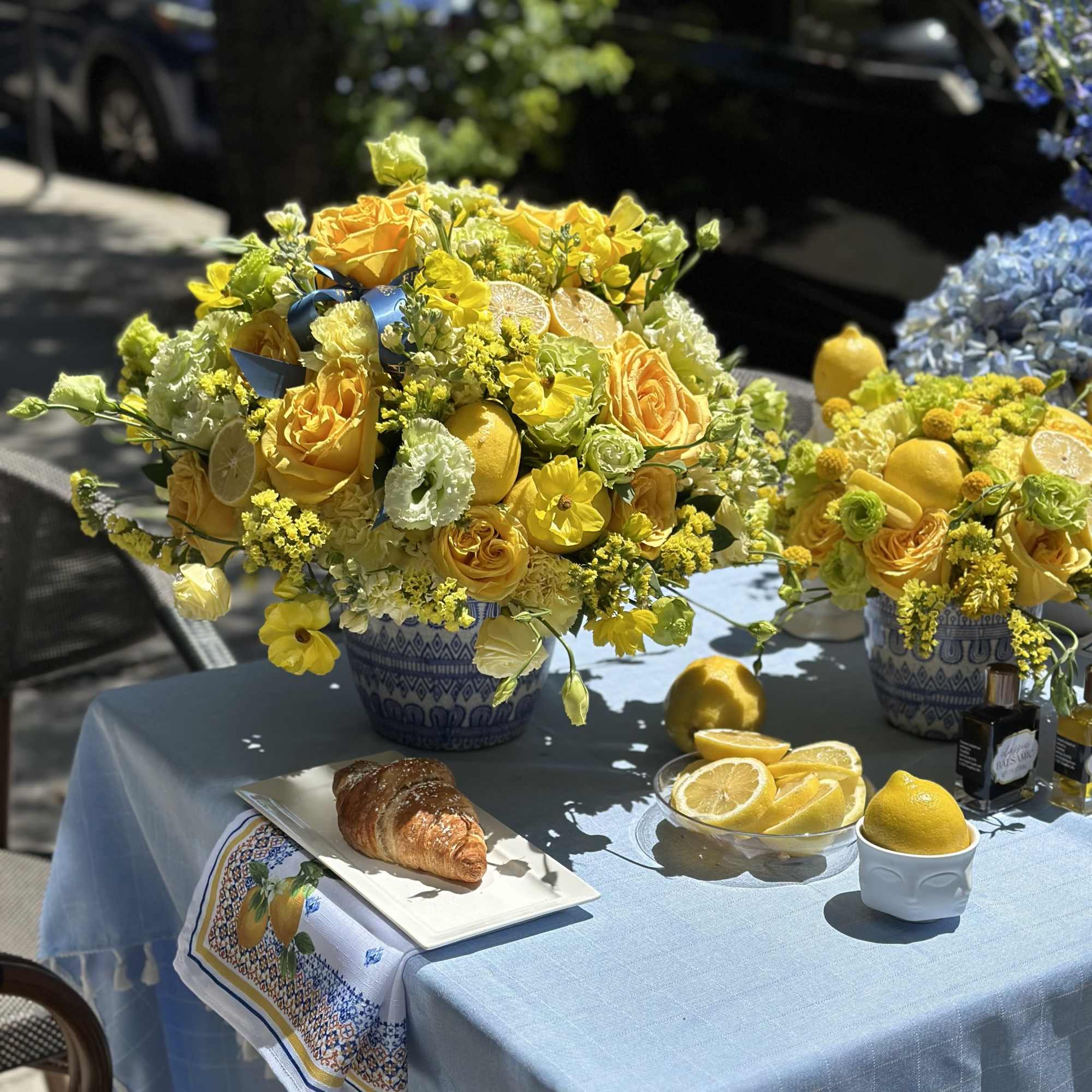 Yellow floral arrangement in a blue patterned vase with lemons and citrus slices