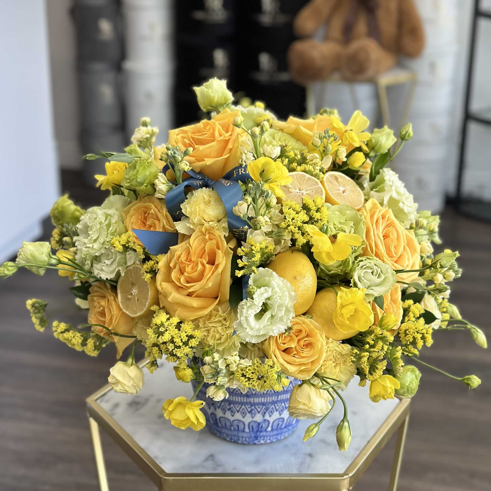 Yellow roses and mixed blooms in a blue-and-white vase with lemon slices