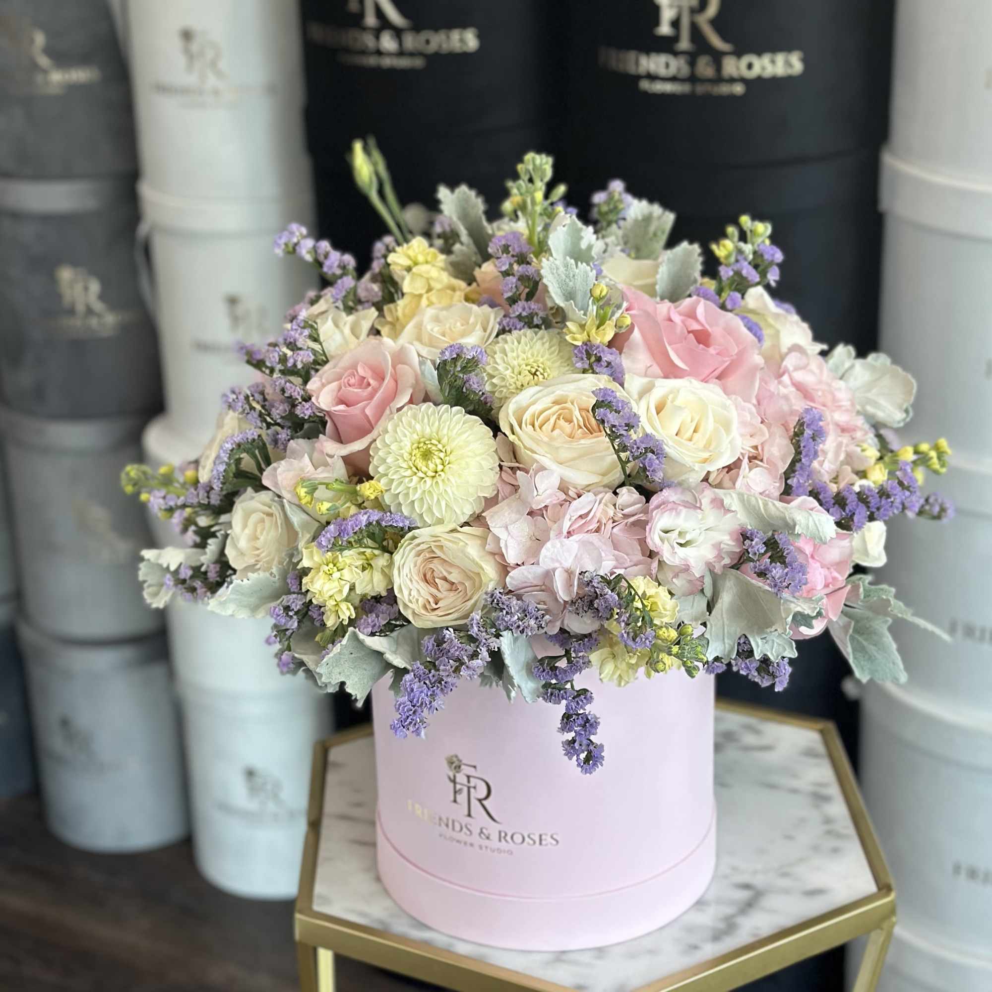 Pastel bouquet of roses and chrysanthemums in a pink hat box