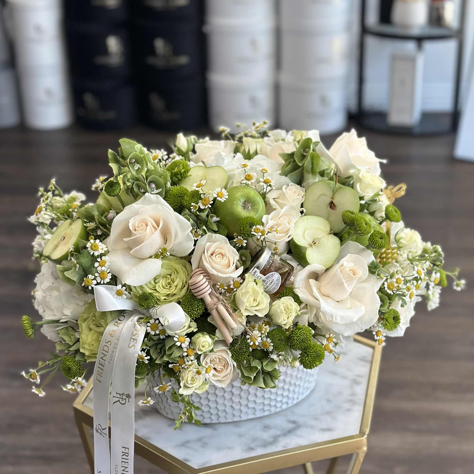 White and green floral arrangement with apple slices in a white vase