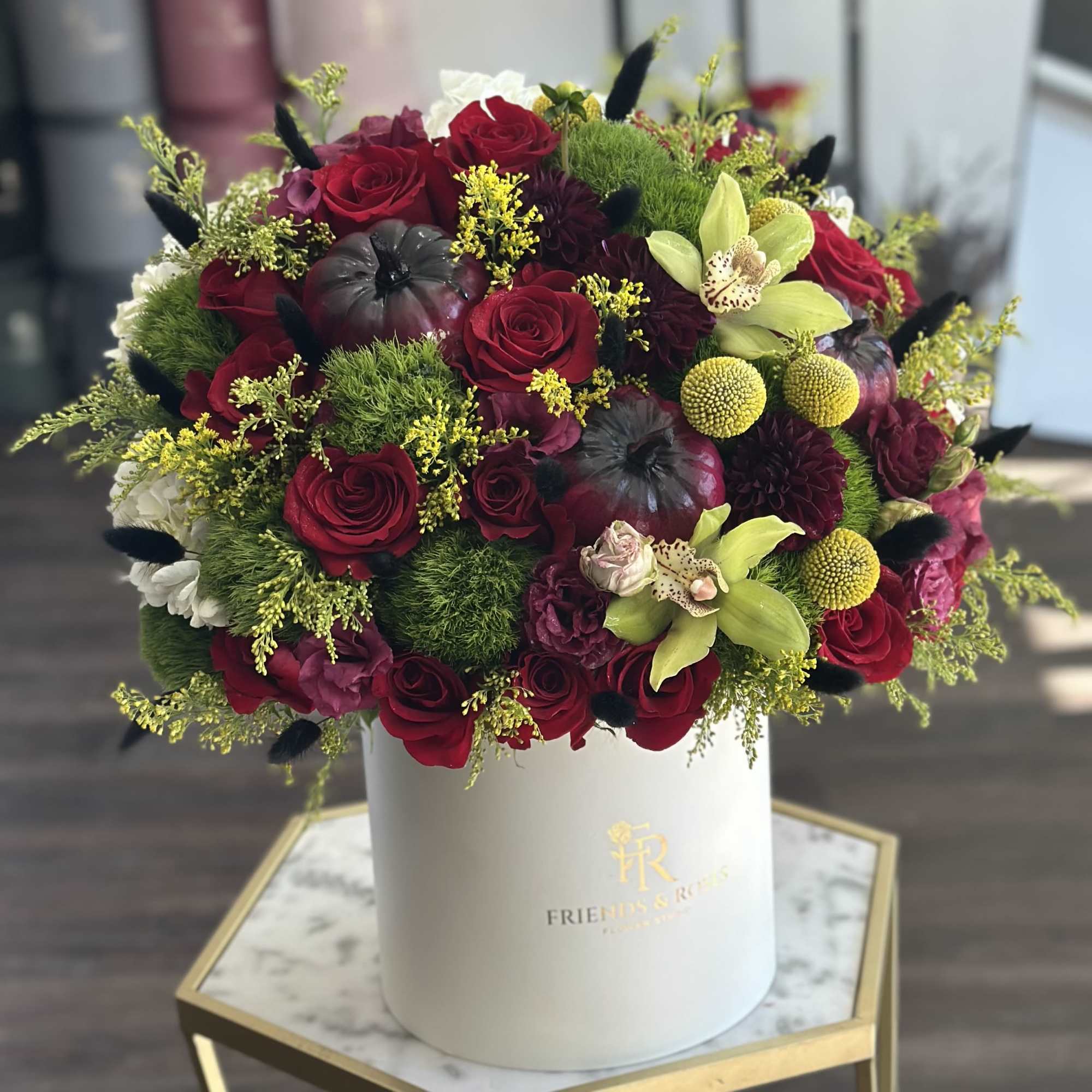 Red roses and green orchids in a white hat box