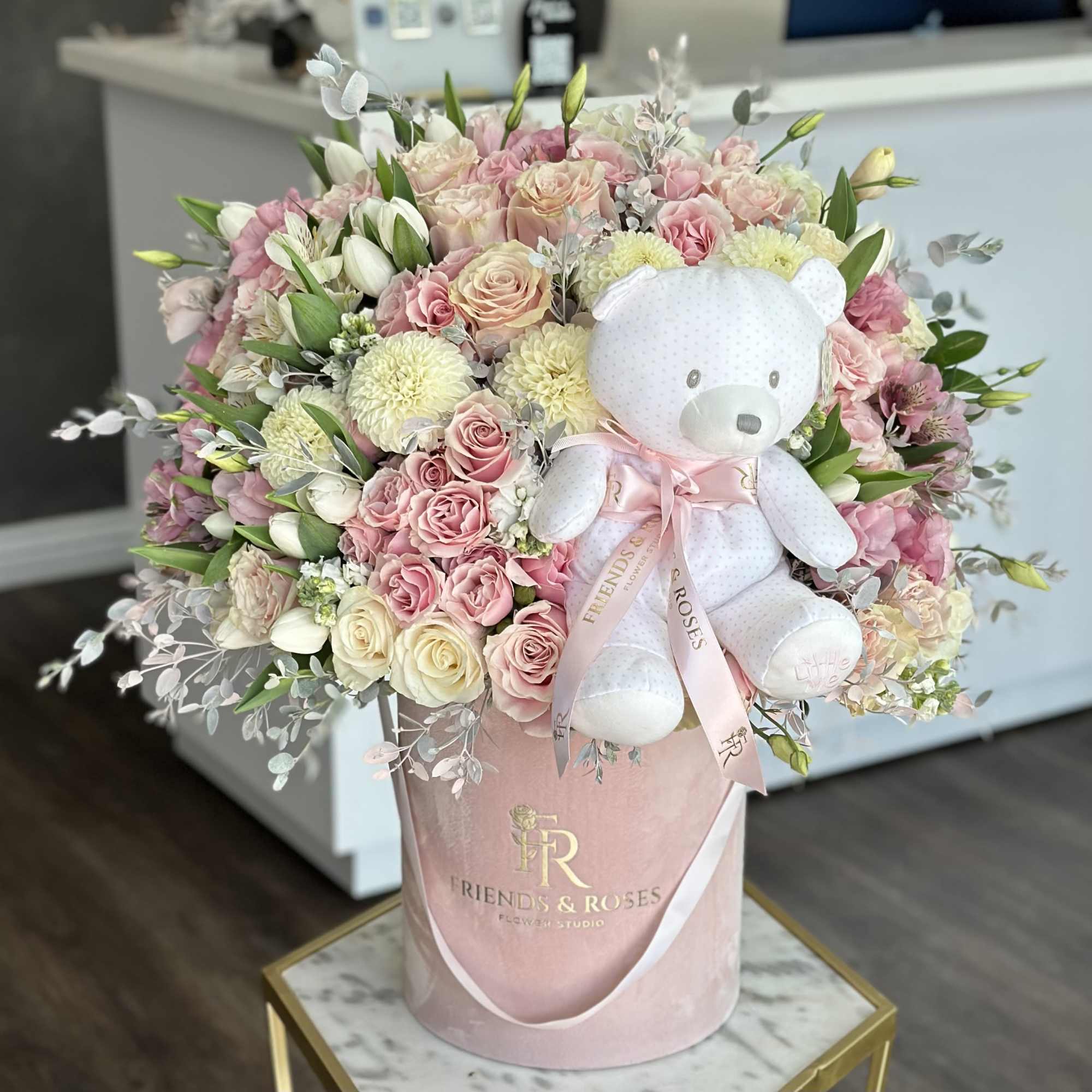 Pink and cream rose bouquet with a white teddy bear in a pink hatbox