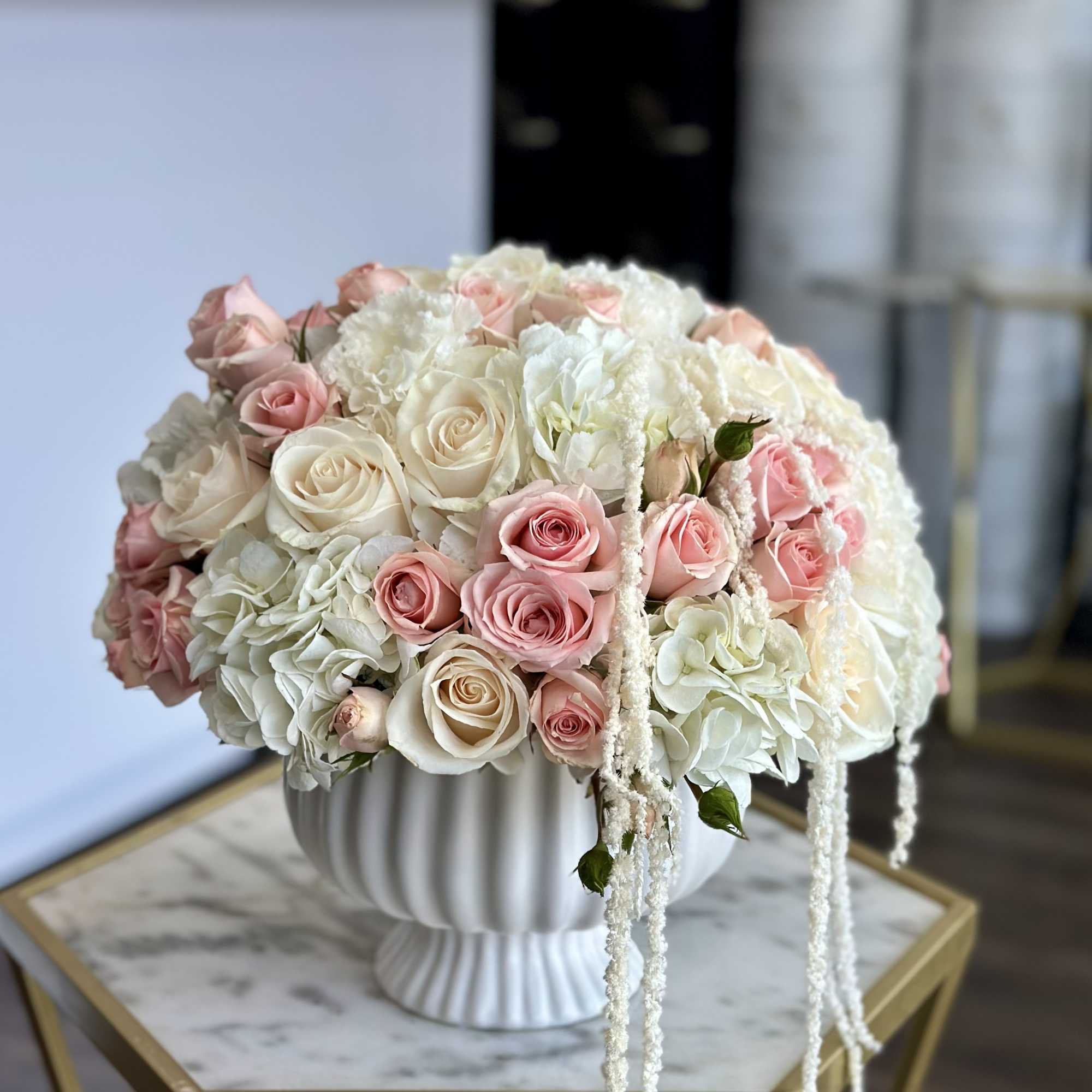 Pink and white roses arranged in a white pedestal vase
