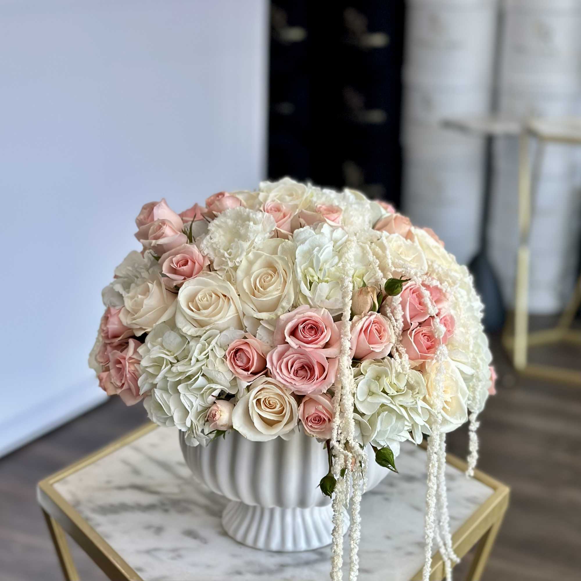 Round bouquet of pink and white roses in a white pedestal vase