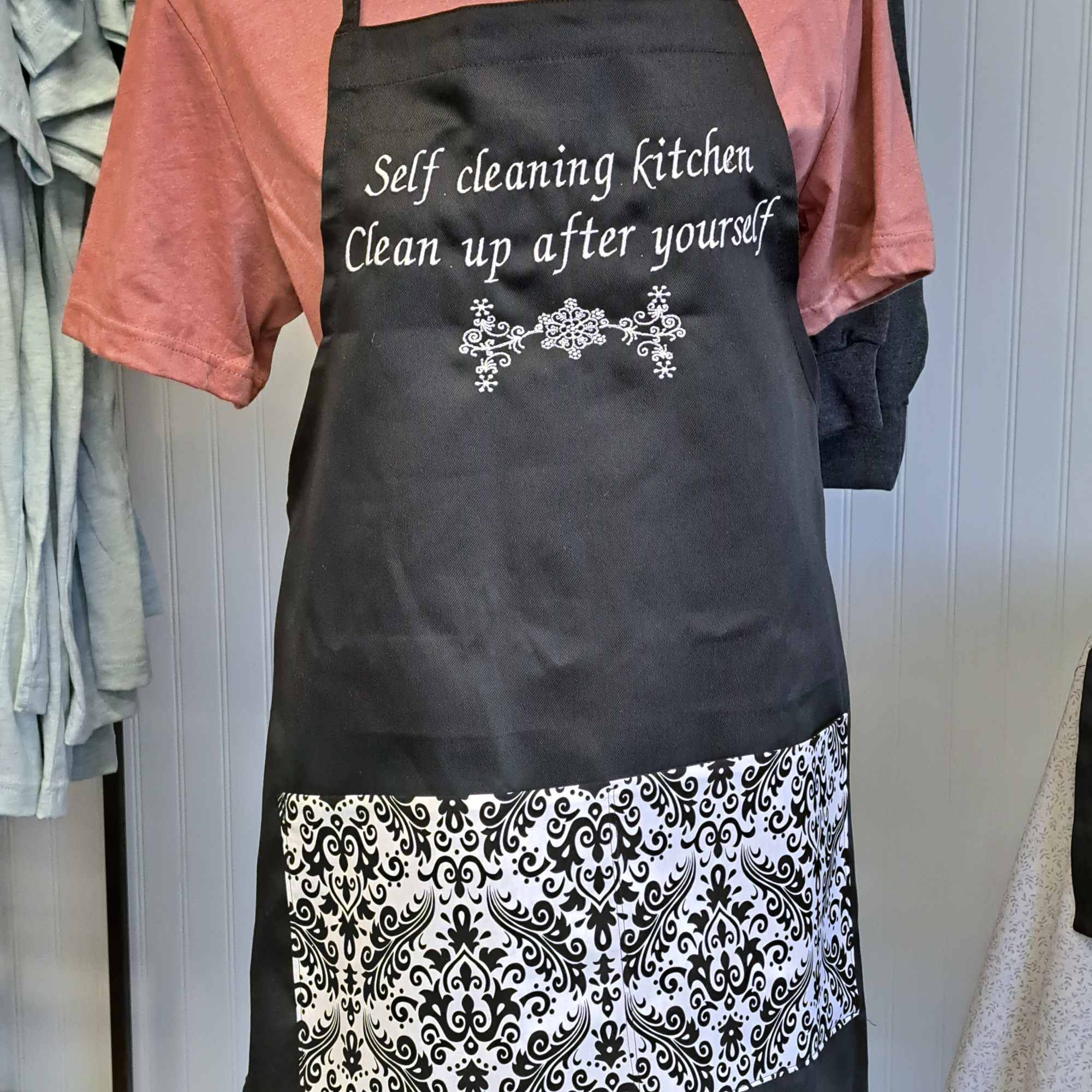 Black apron with white text over a pink shirt