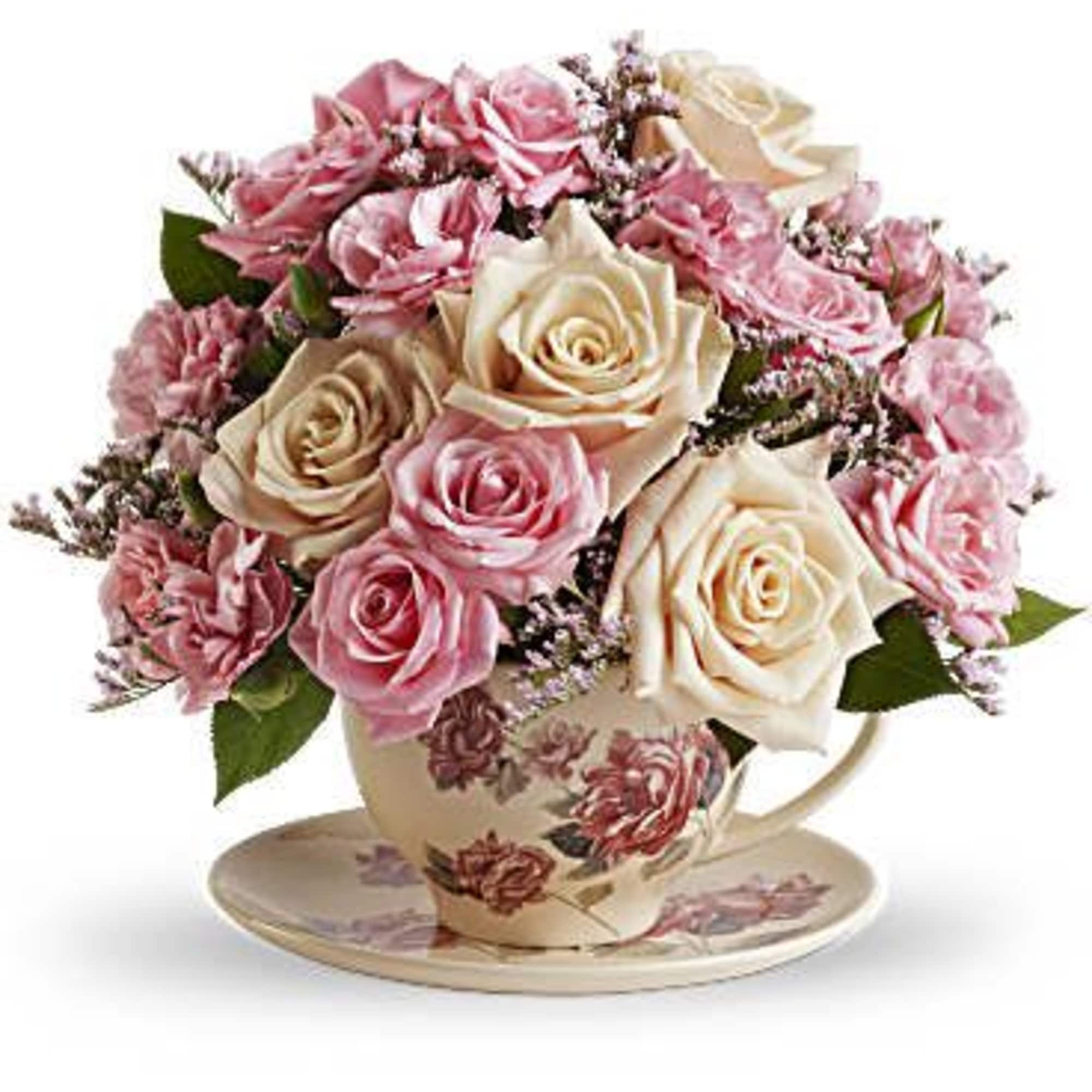 Pink and cream roses arranged in a floral teacup with saucer